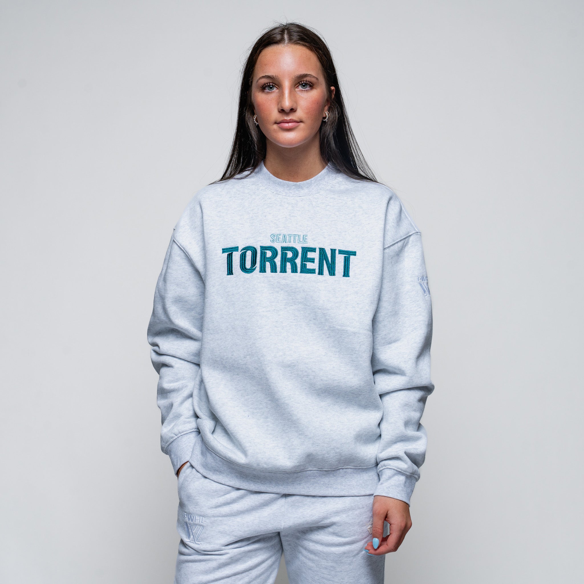 Person wearing a light gray sweatshirt with 'Seattle Torrent' text on a plain background