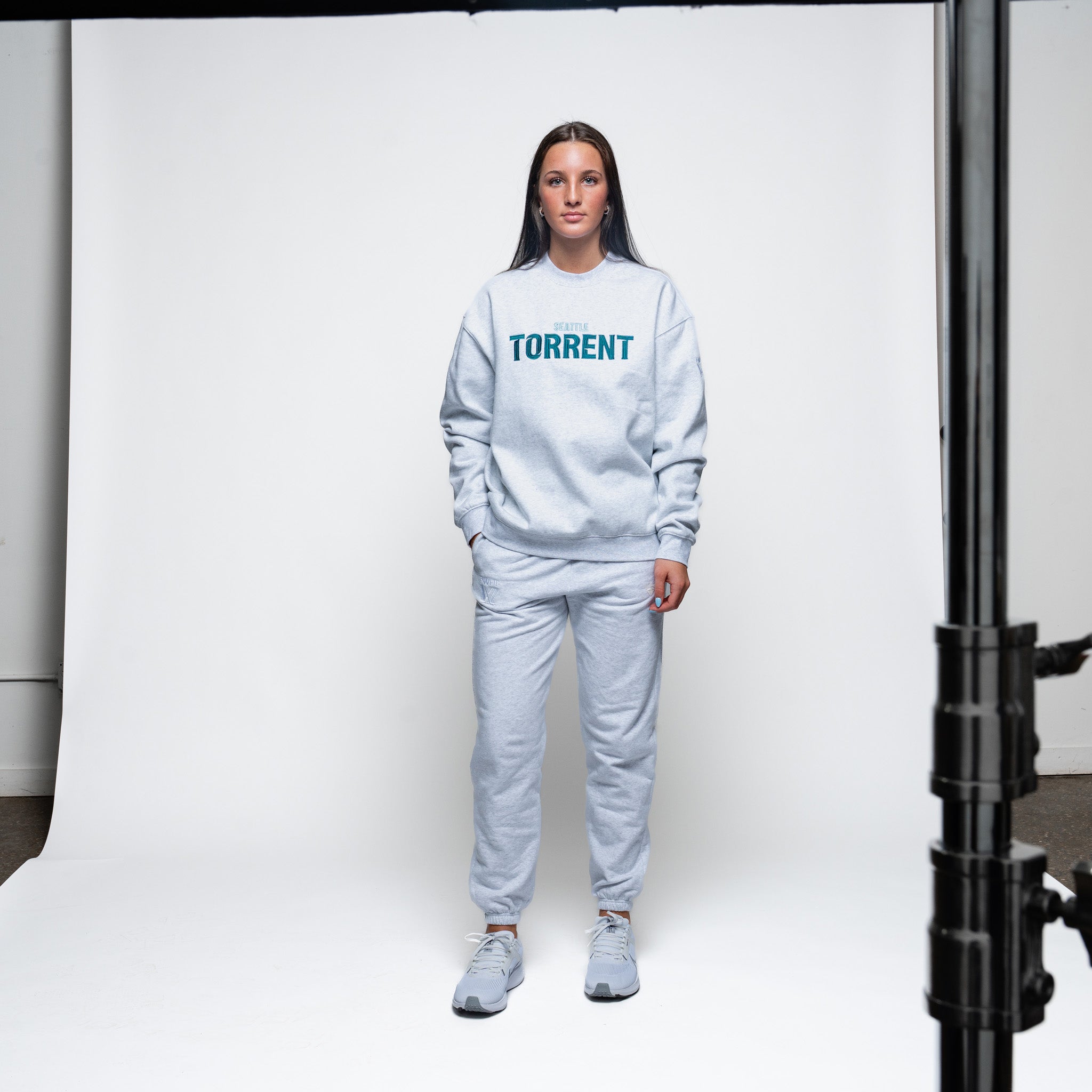 Person wearing a light gray 'TORRENT' sweatshirt and pants on a white background