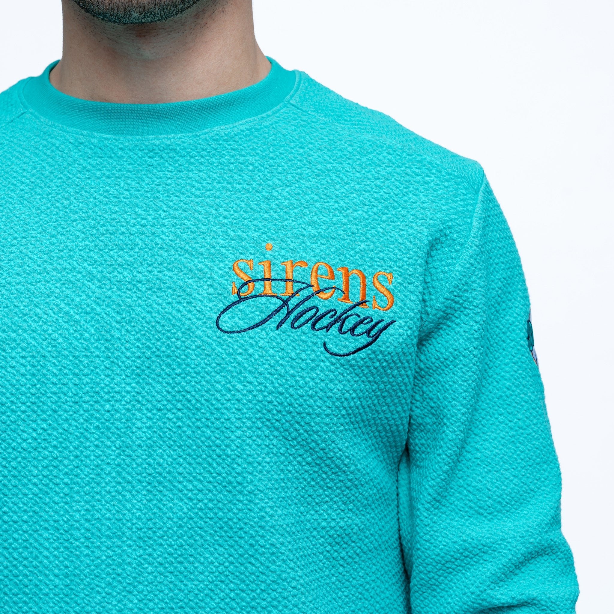 Teal sweatshirt with 'sirens hockey' text on a white background