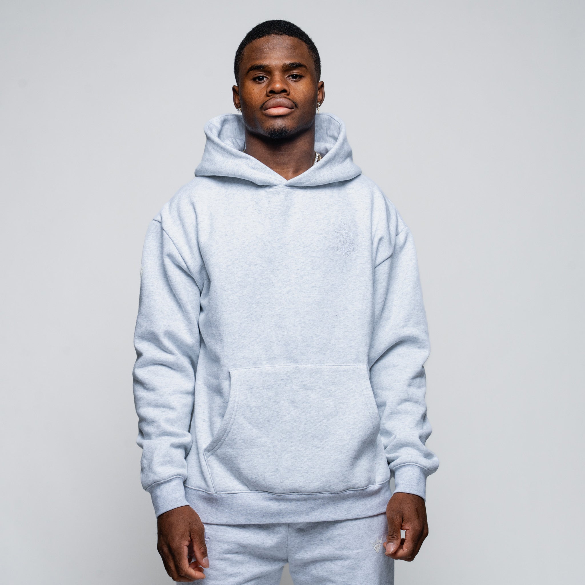 Person wearing a light gray hoodie and pants on a plain background