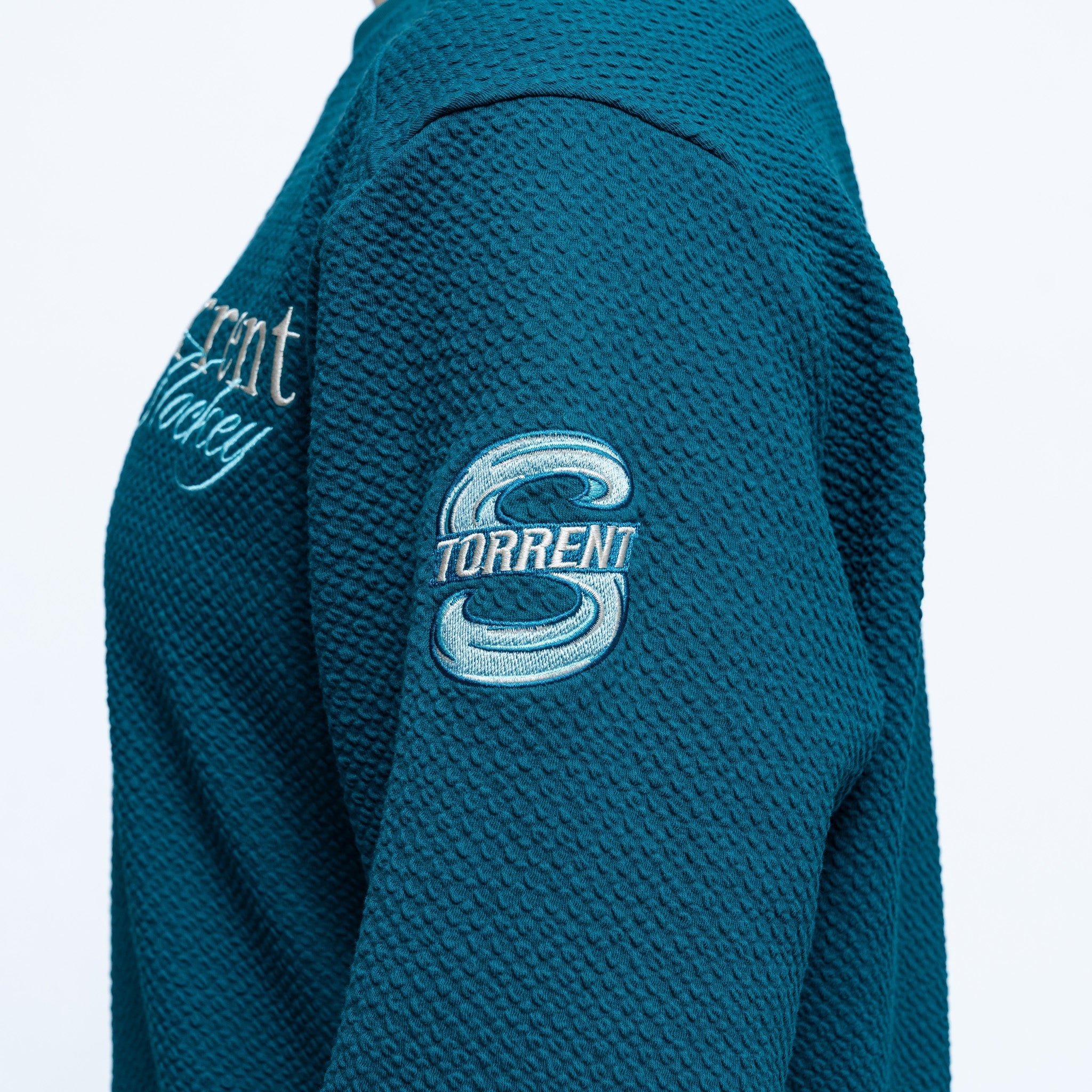Teal textured jacket with 'Torrent' logo on a white background