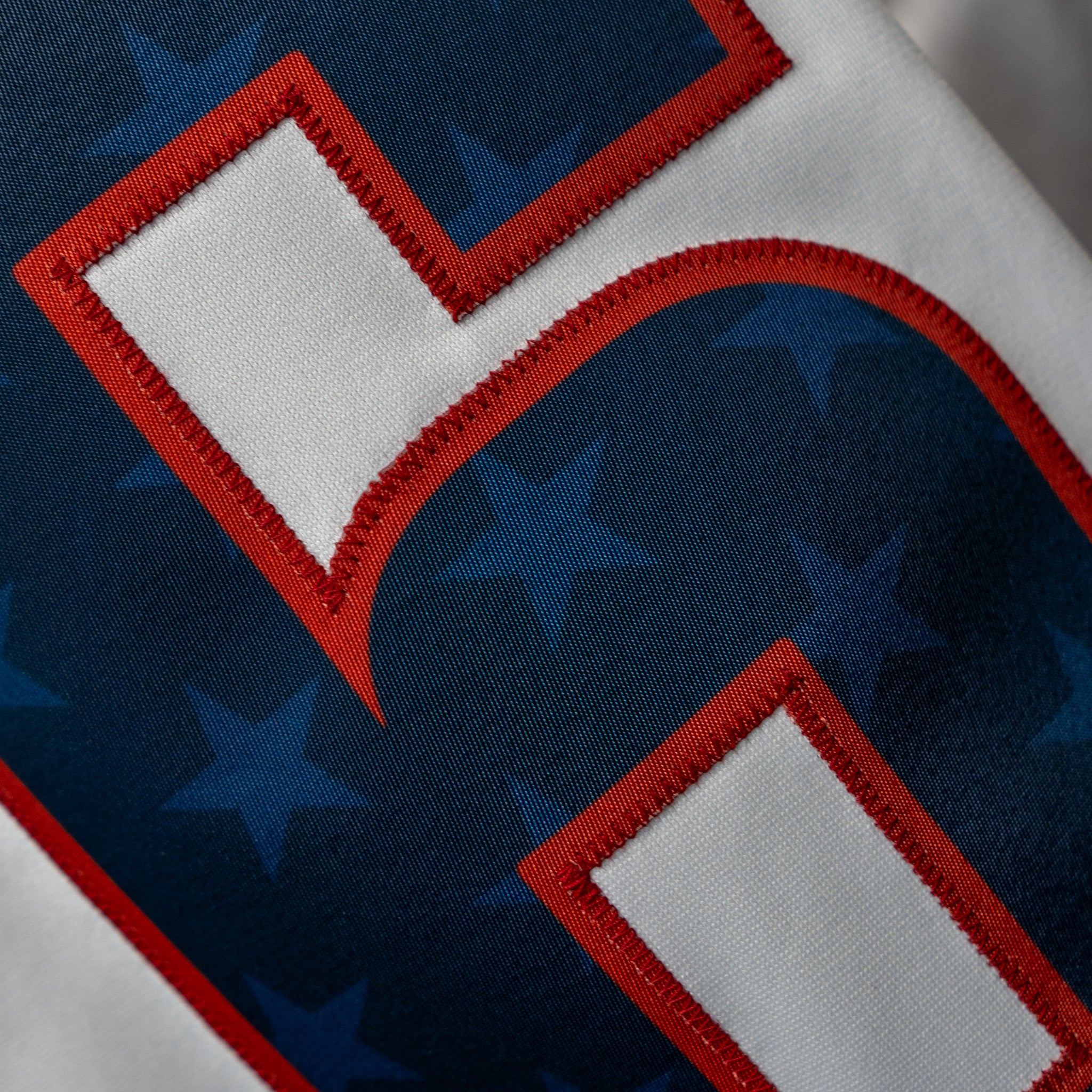 Close-up of the 6 on the back of the jersey with red stitching and navy 6 with blur stars inside the number