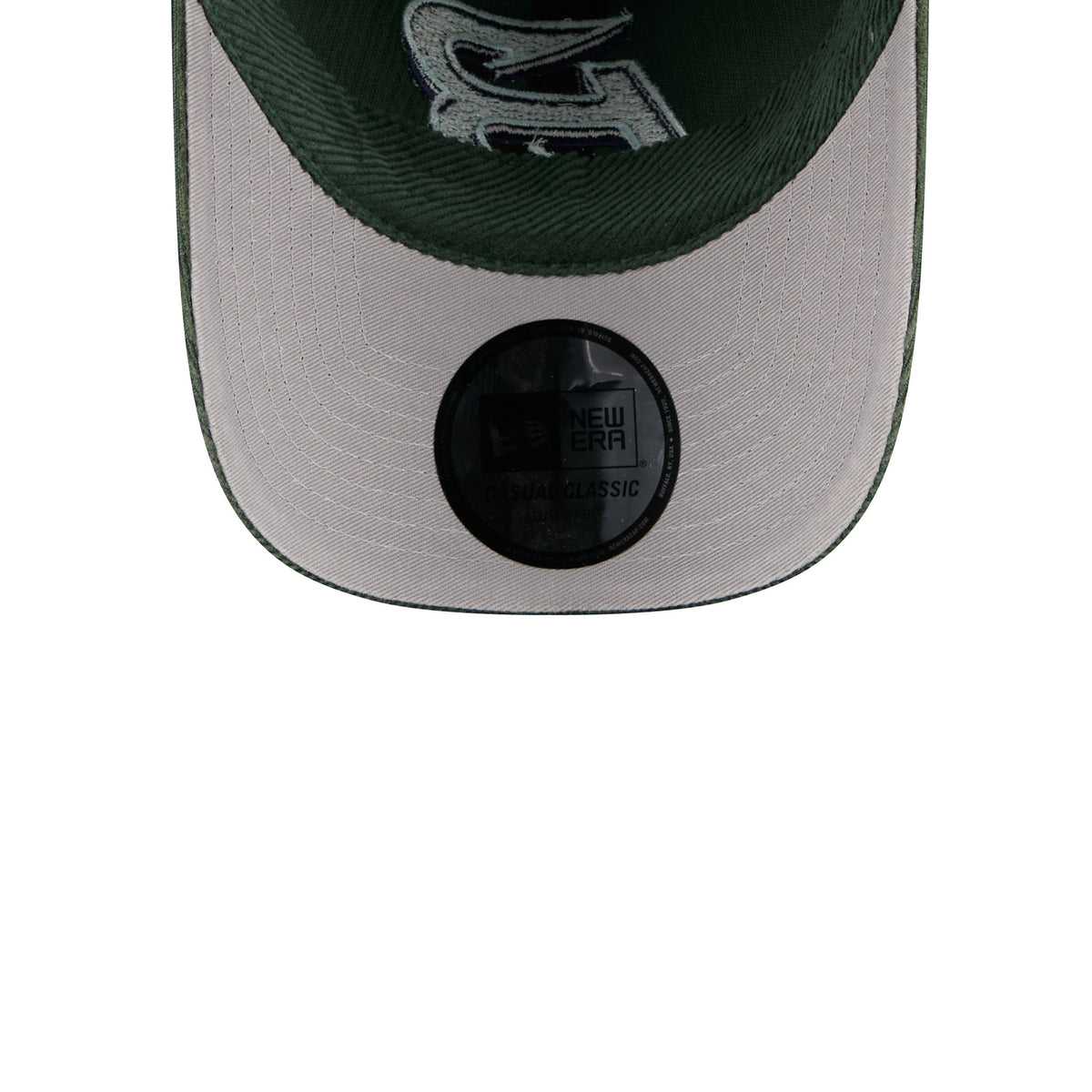 Close-up of the underneath of a New Era baseball cap in dark green and light gray, showing the embroidered lettering and the black size/brand sticker on the visor.