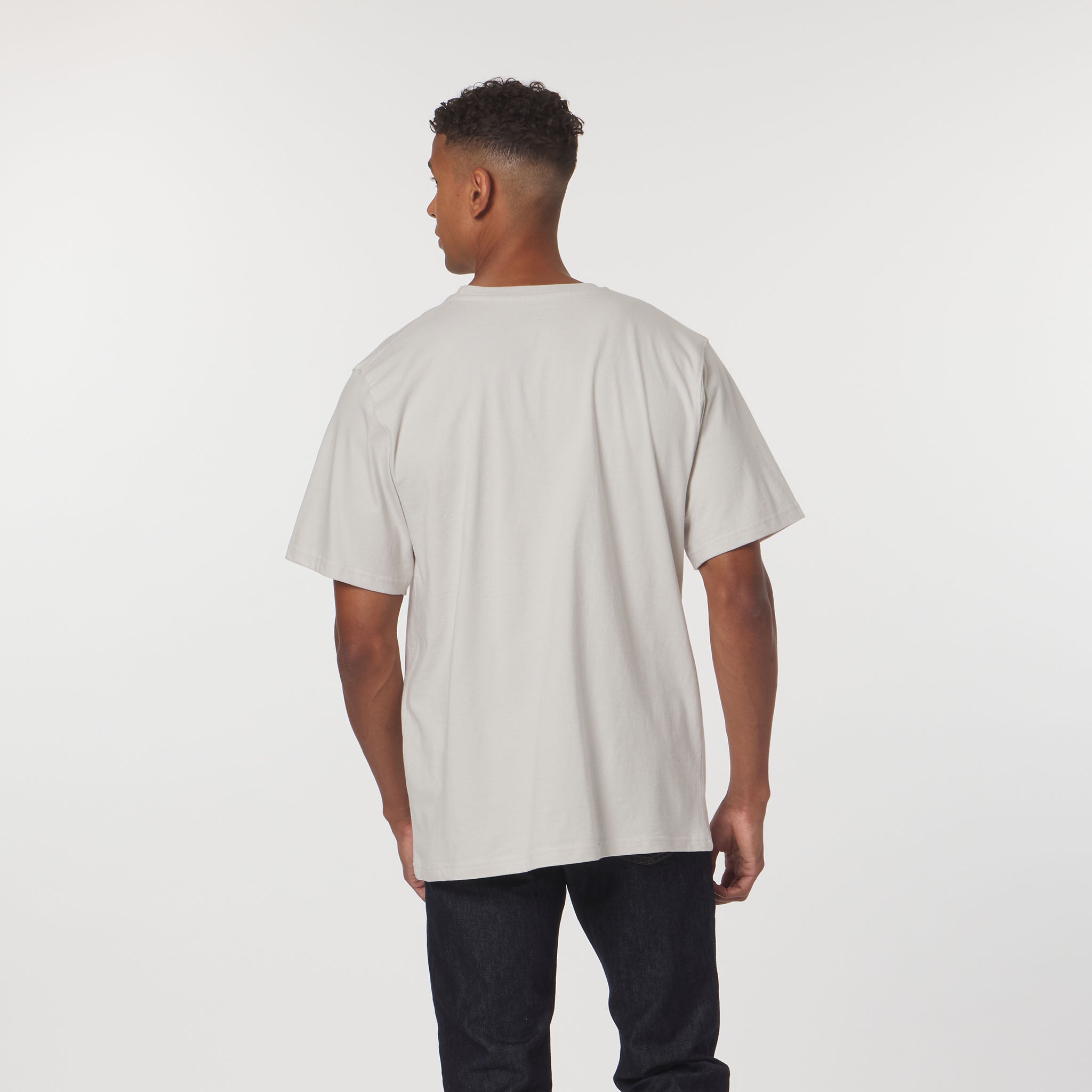 Person wearing a beige t-shirt and dark pants on a white background