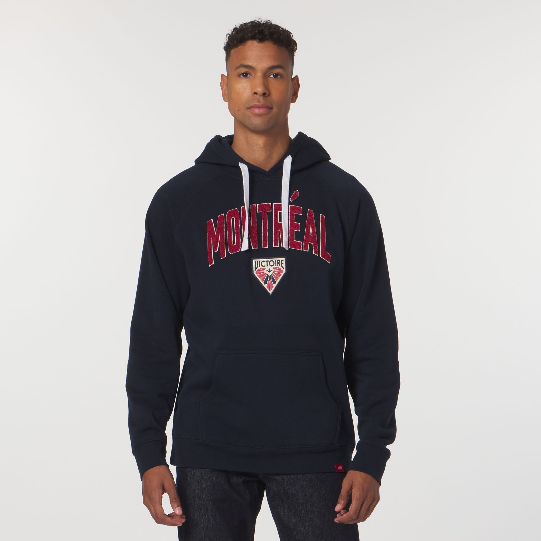 Man wearing a navy hoodie with 'Montreal' printed on it against a white background