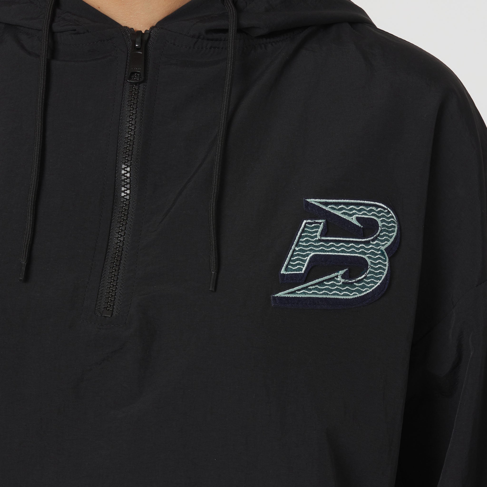 Black hoodie with a distinctive logo on the chest against a neutral background