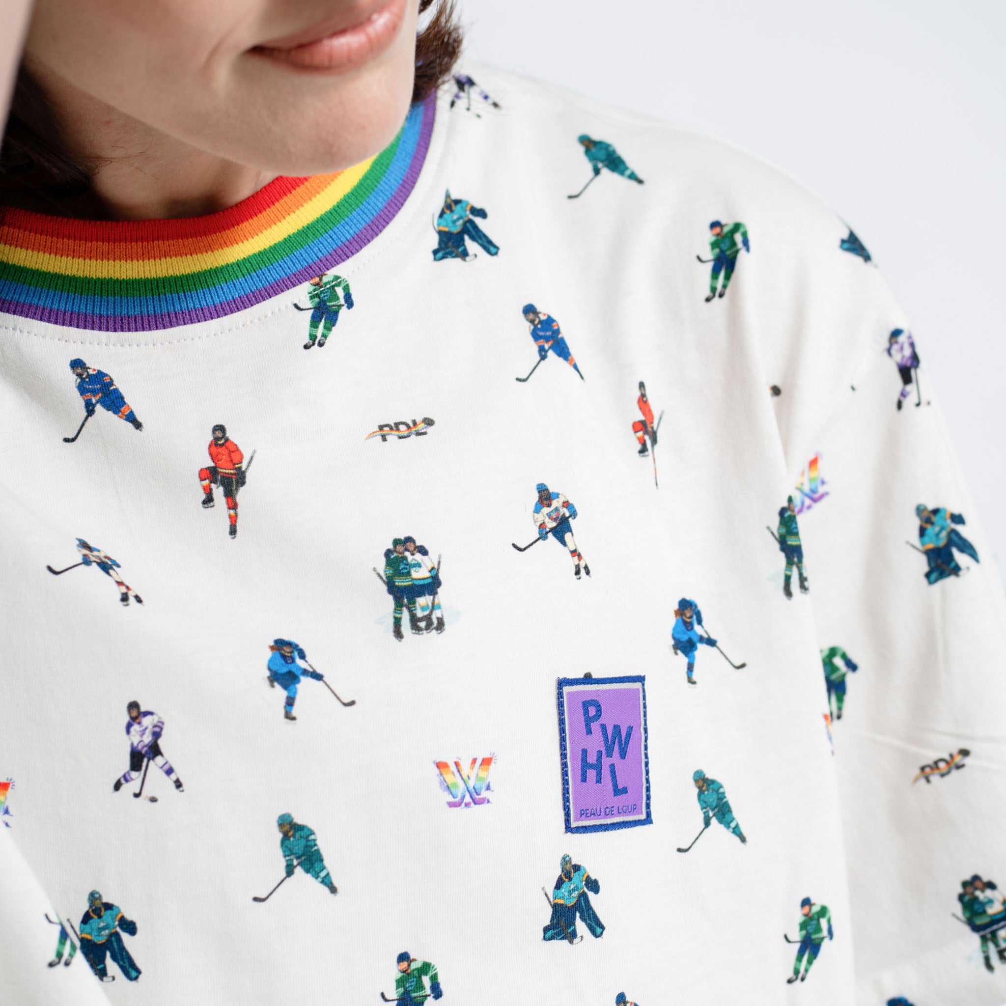 Close-up of a white sweatshirt with hockey player patterns and a rainbow design on the collar.