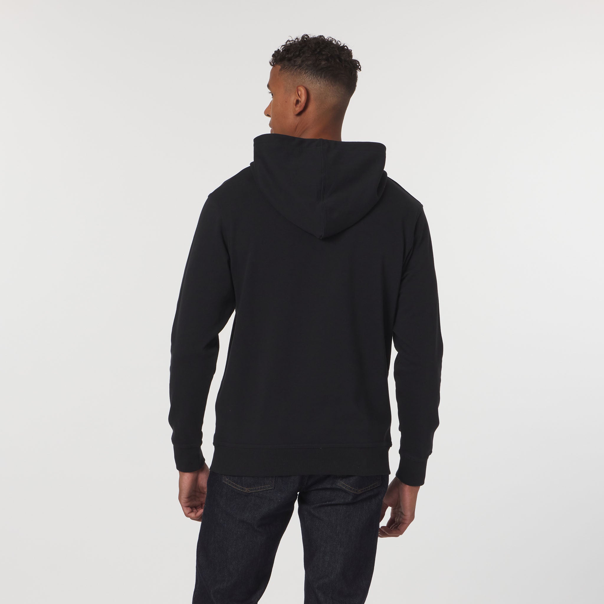 Person wearing a black hoodie from behind on a white background