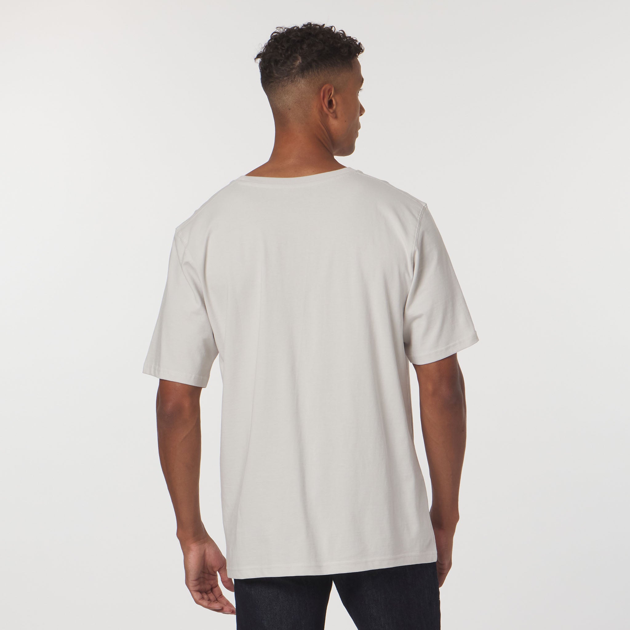 Man wearing a plain white t-shirt against a light gray background