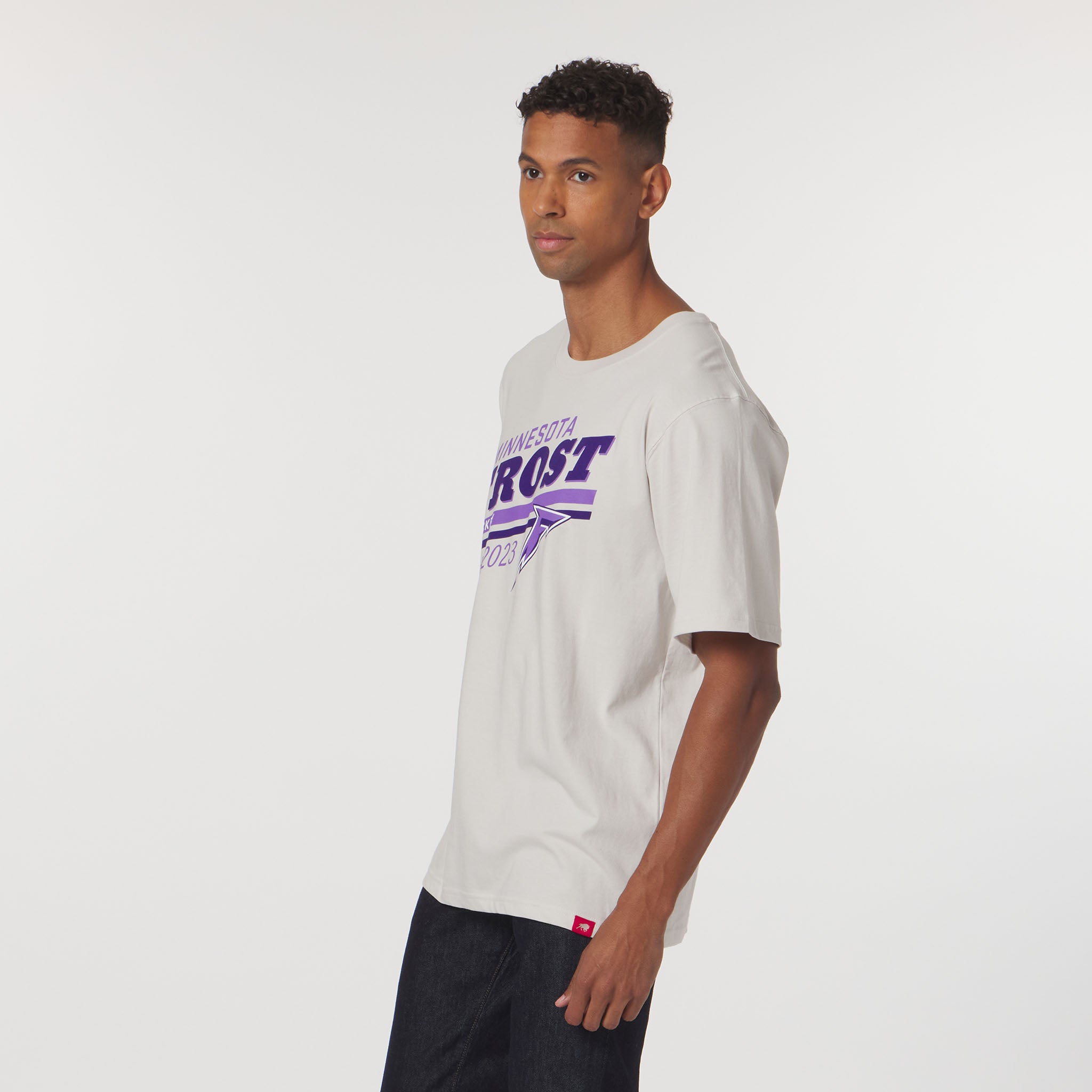 Man wearing a light gray t-shirt with purple text on a white background