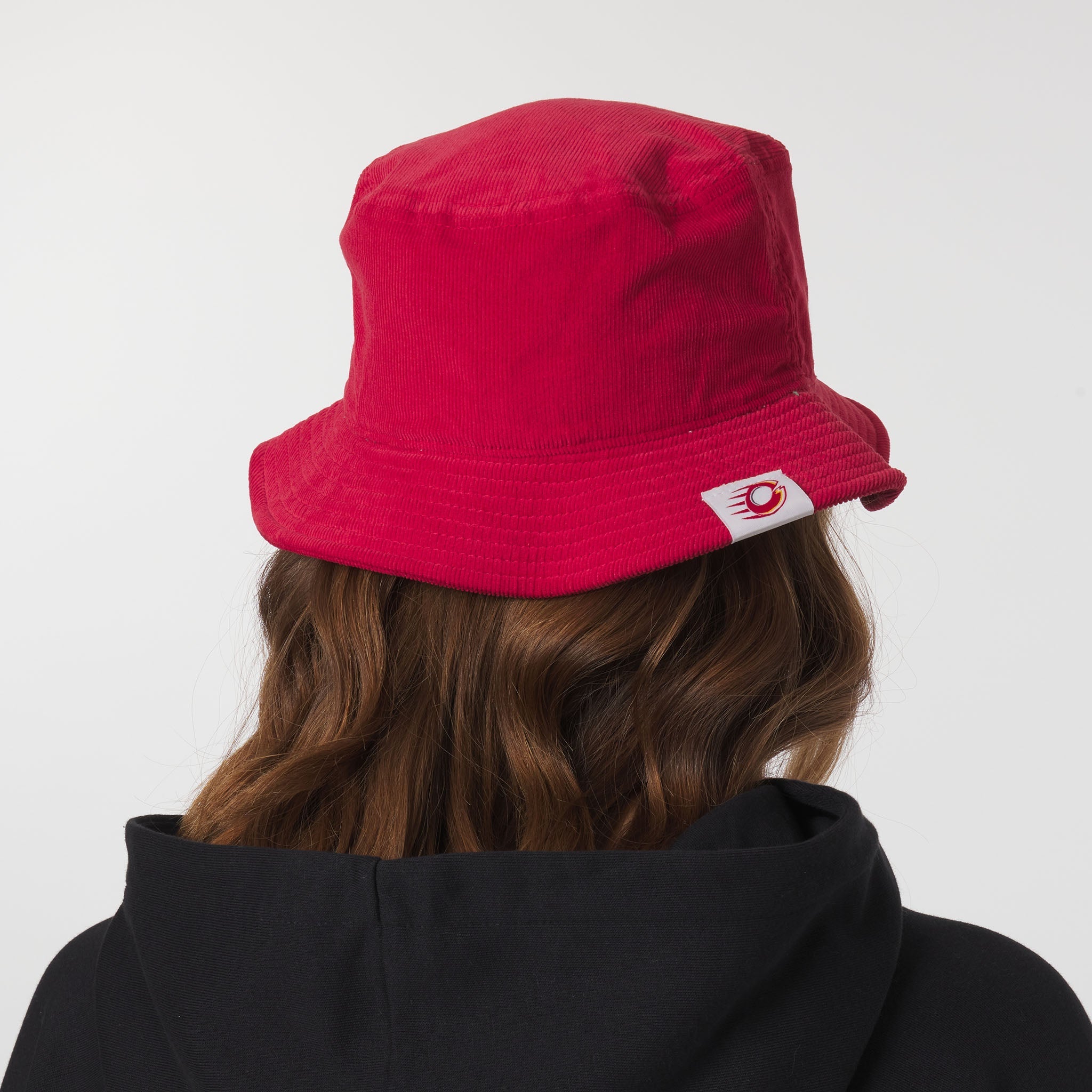 Red bucket hat with a brand logo worn by a person on a white background