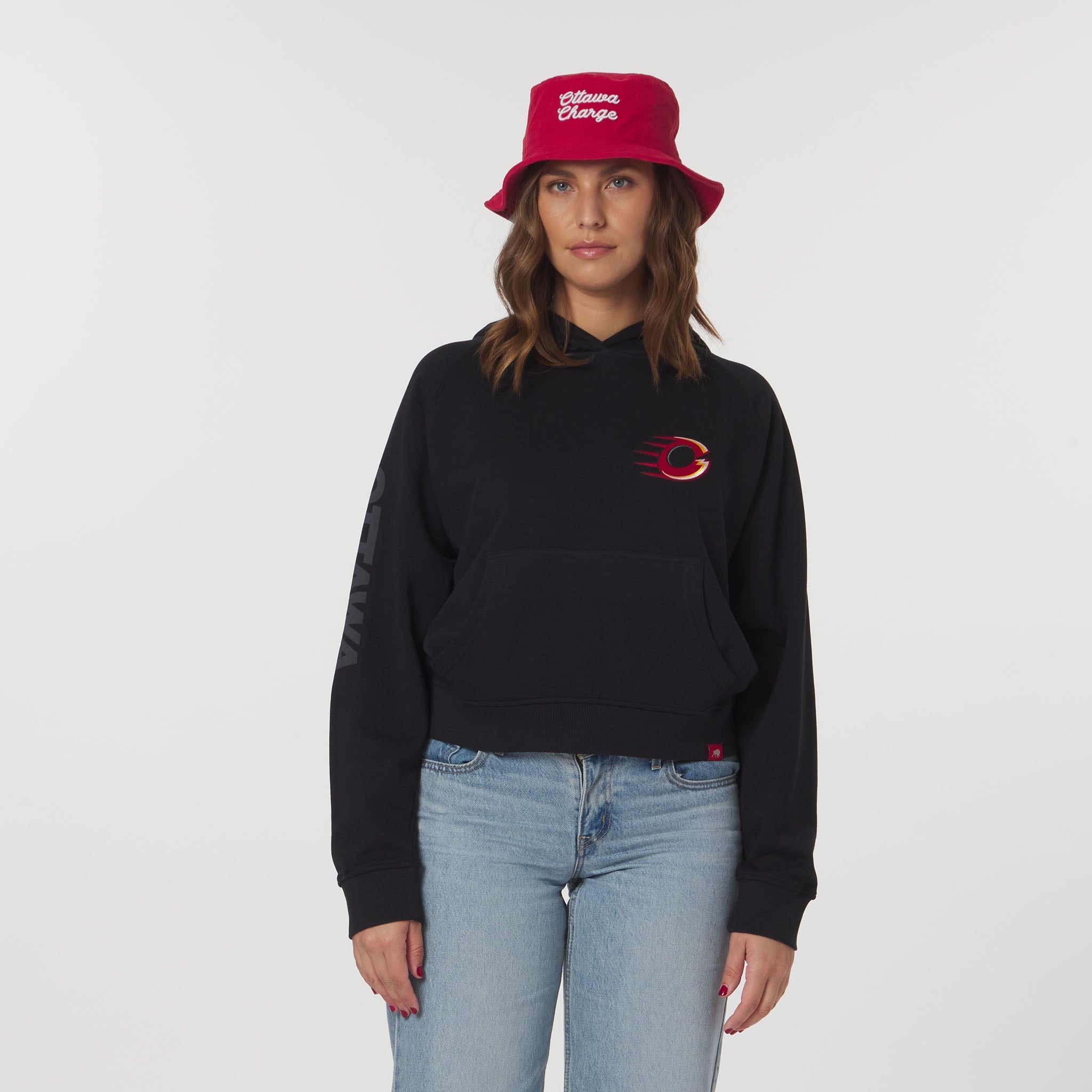 Person wearing a black hoodie with a red logo and a red bucket hat on a white background