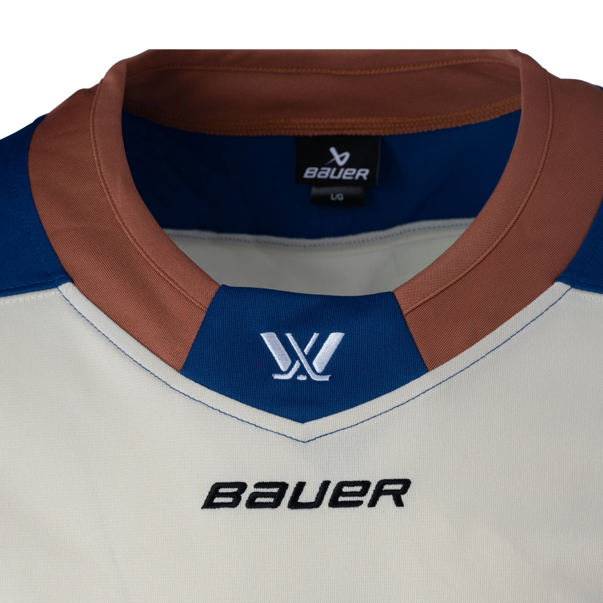 Front of a cream-colored jersey with a tan collar has a blue color block with the PWHL logo and the Bauer logo is beneath it.