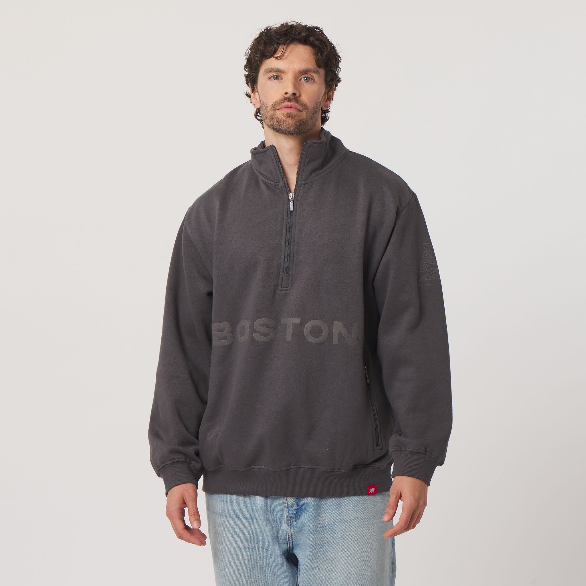 Man wearing a dark gray sweatshirt with 'BOSTON' branding on a plain background