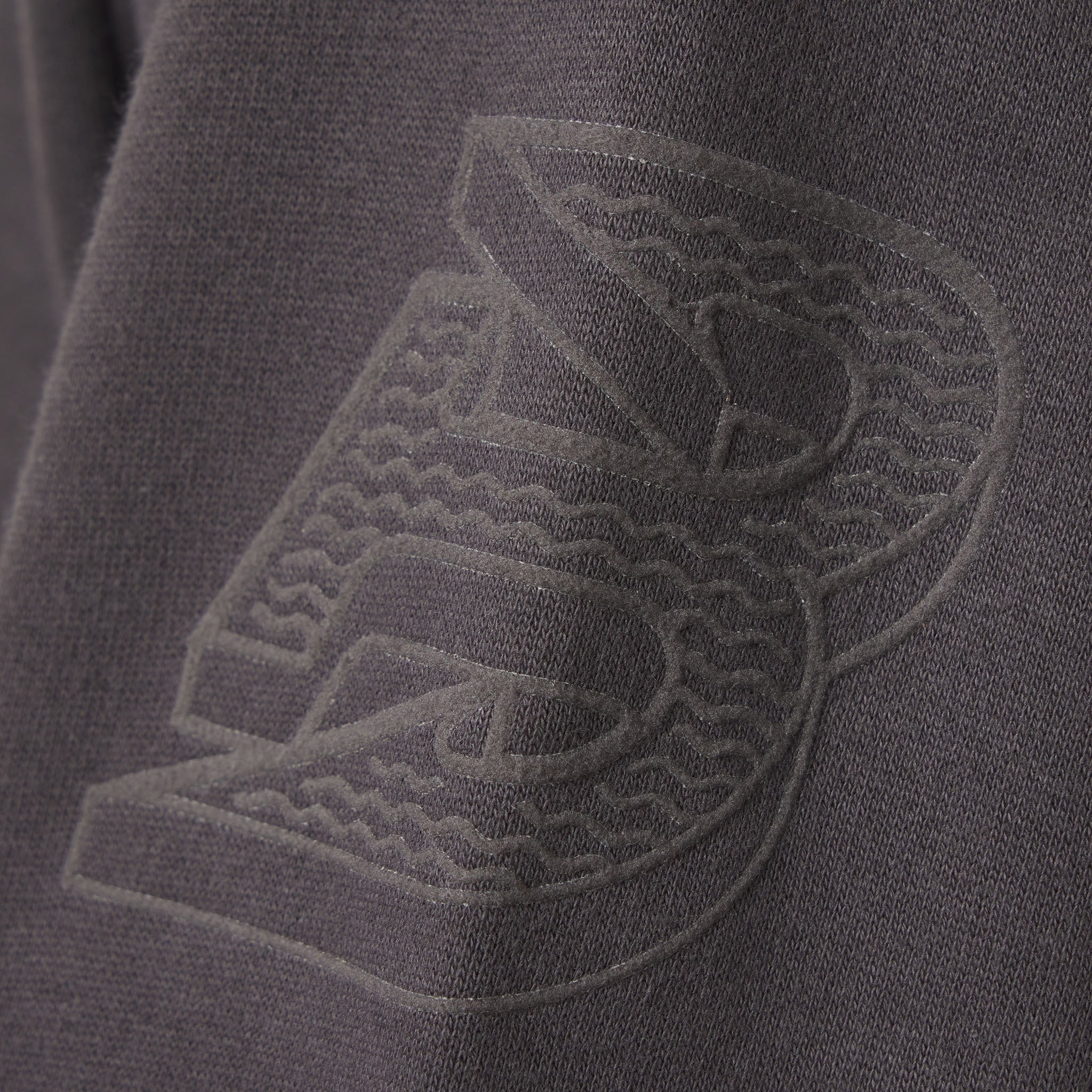 Close-up of a textured logo on a dark fabric surface