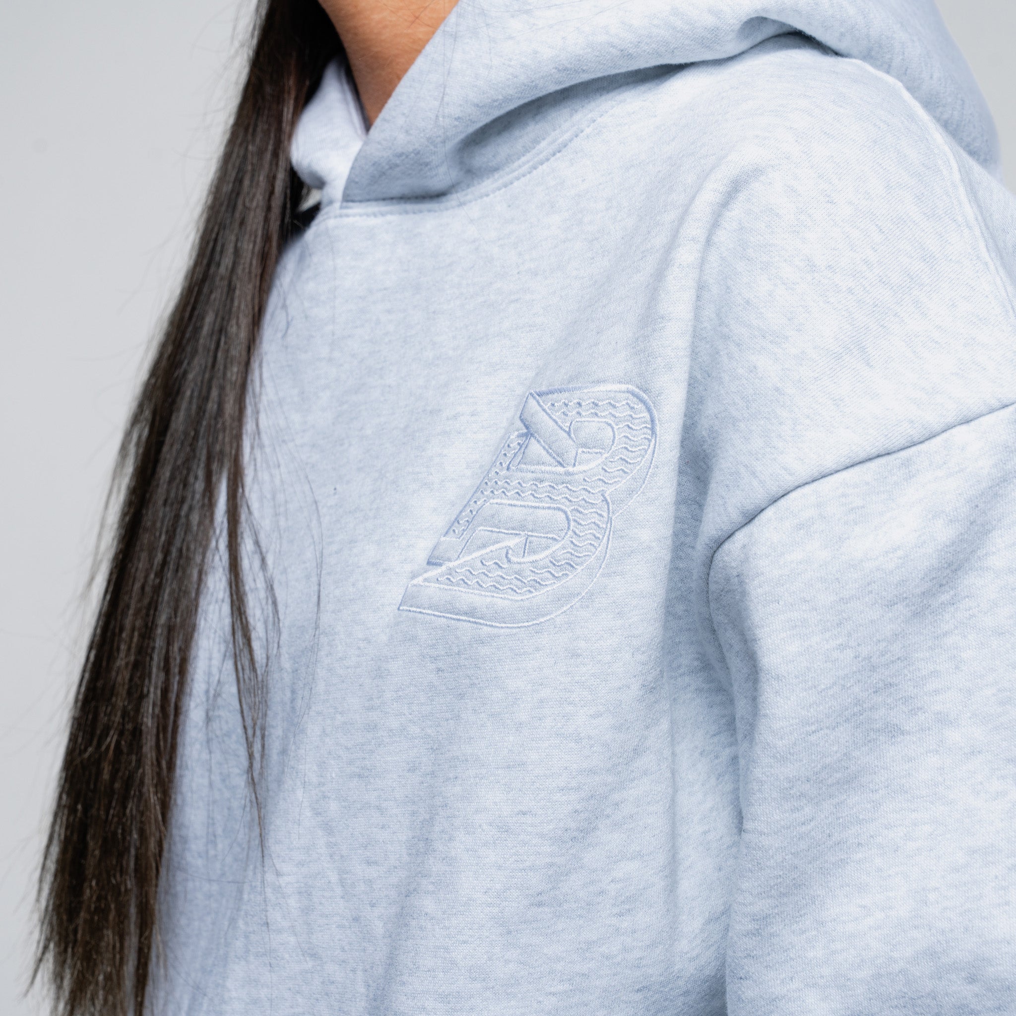 Light grey hoodie with a logo on the chest against a neutral background