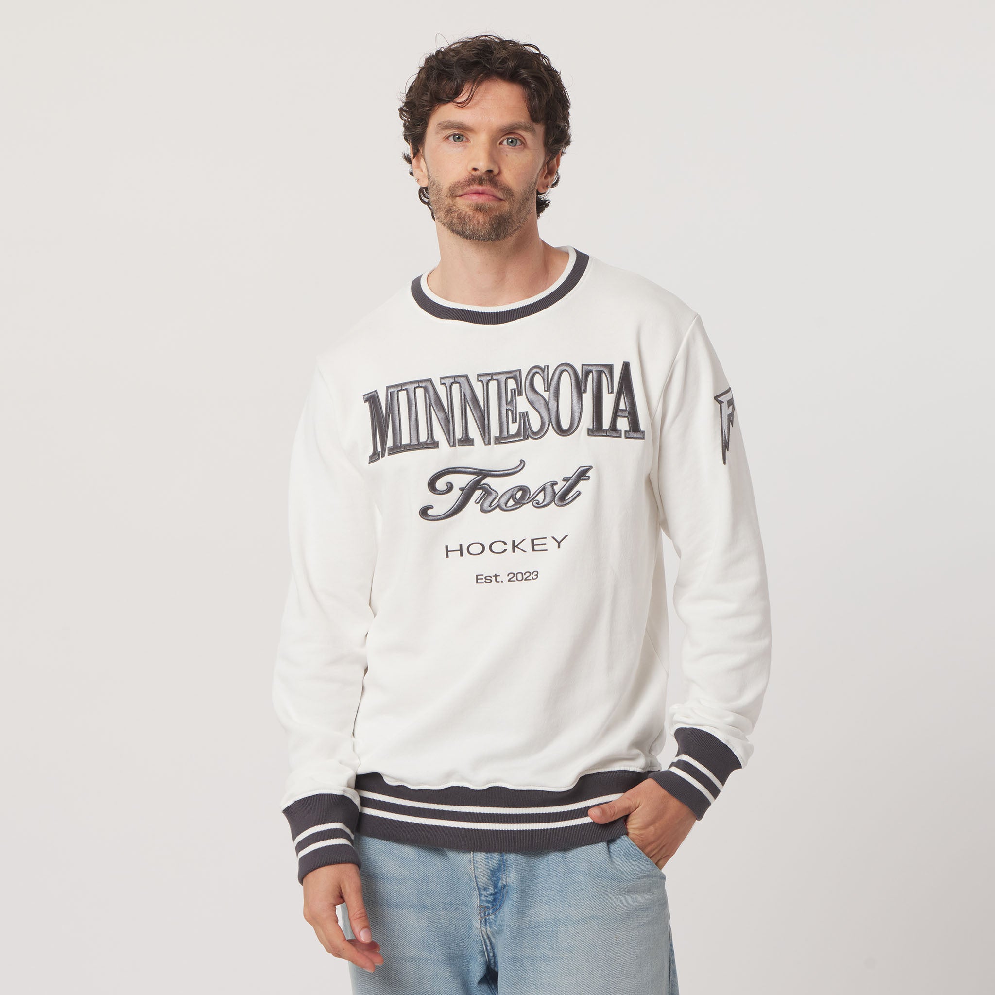 Man wearing a white sweatshirt with 'Minnesota Frost Hockey' text on a plain background