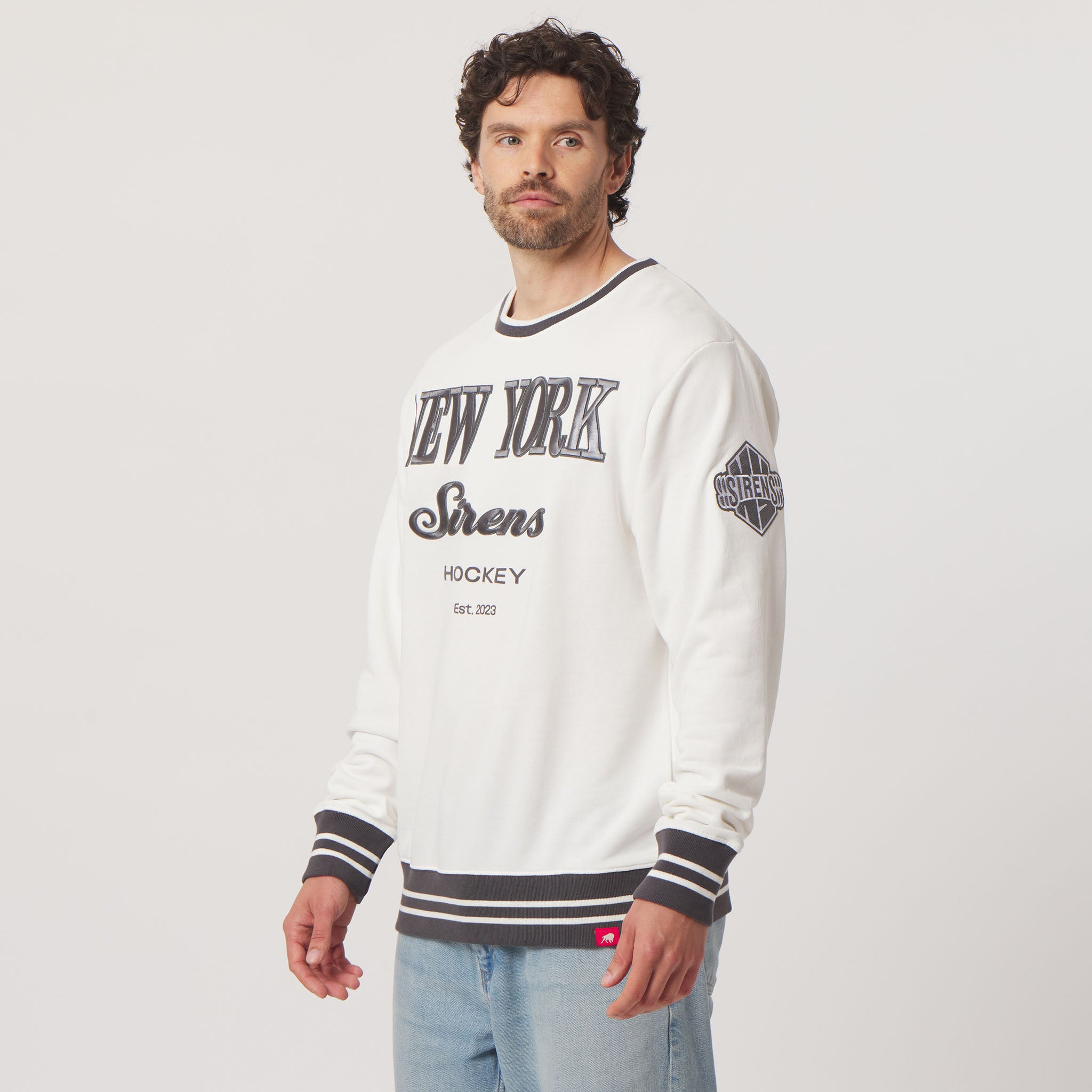 Man wearing a white sweatshirt with 'New York Sirens Hockey' text on a light gray background