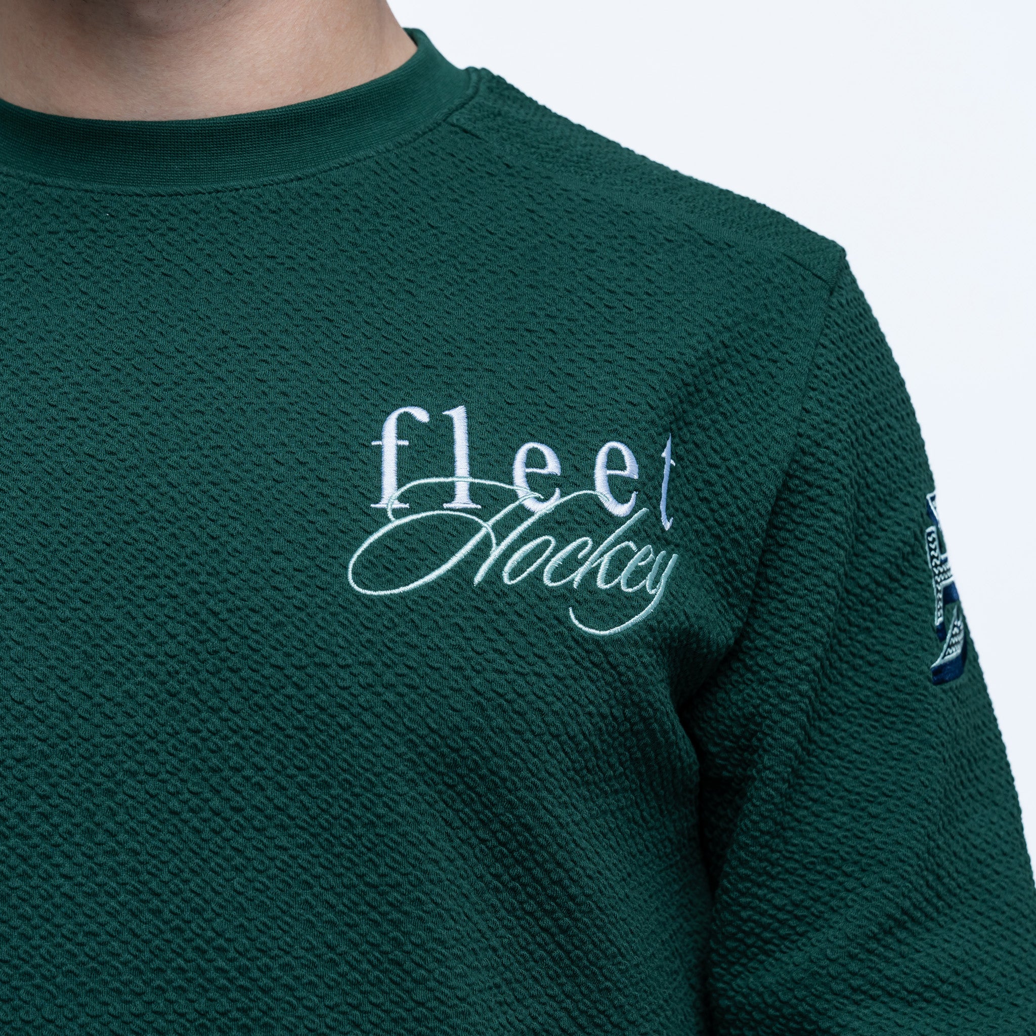 Green sweatshirt with 'fleet hockey' text on a plain background