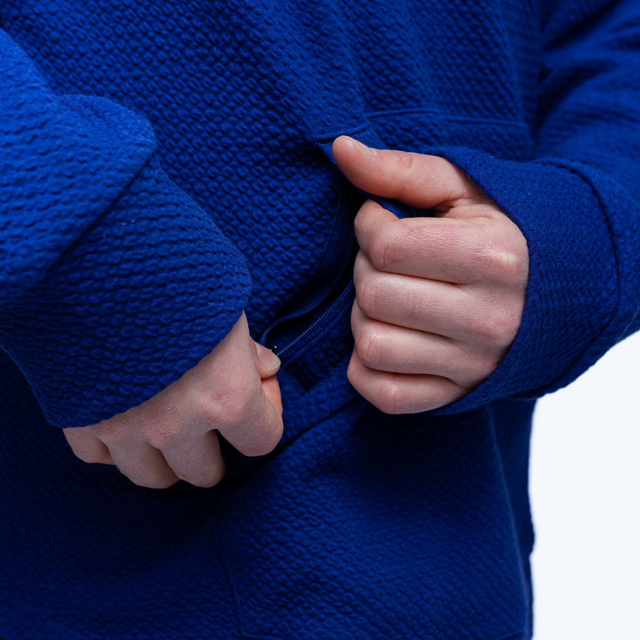 Close-up of hands in a blue textured garment against a white background