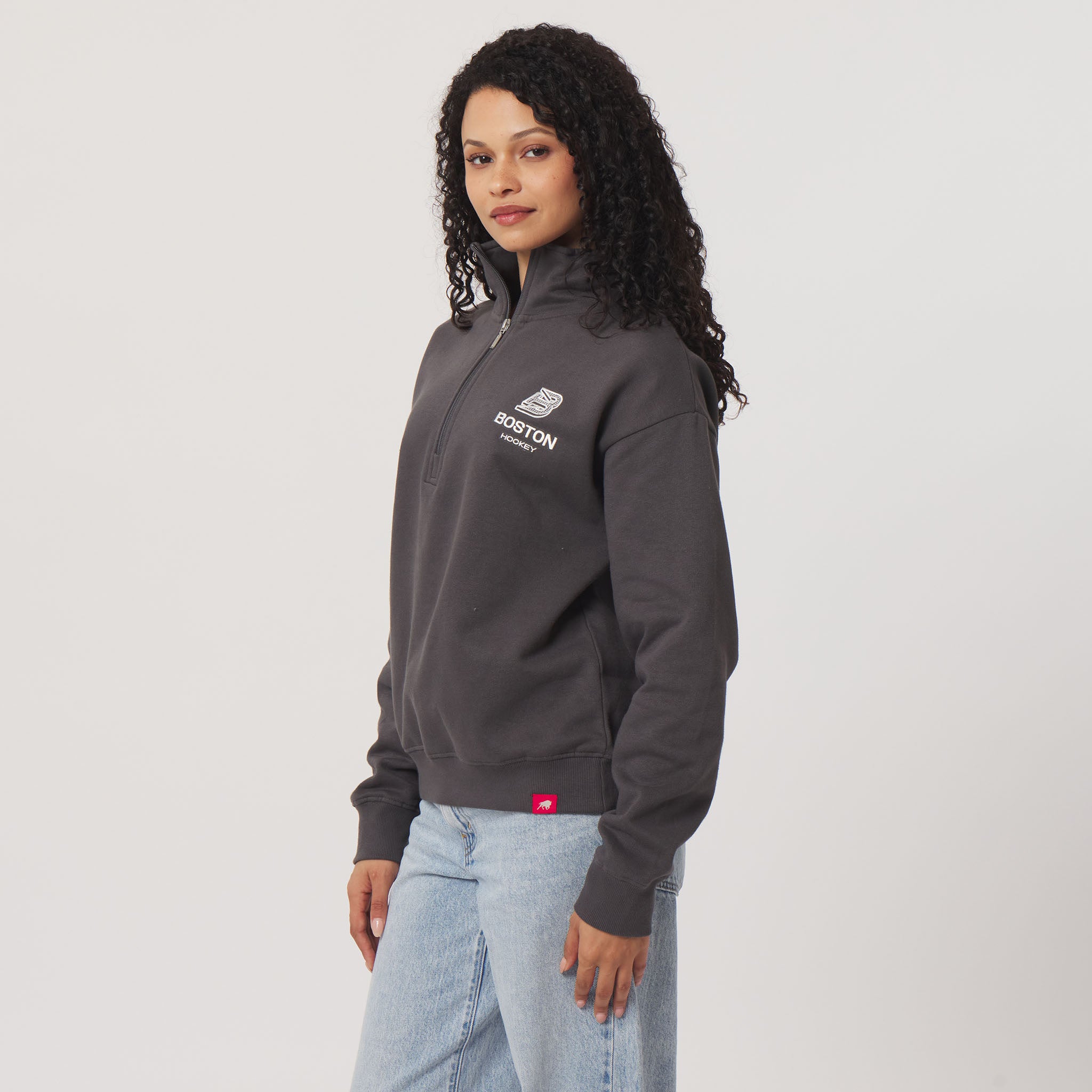 Woman wearing a gray jacket with a logo on a light gray background