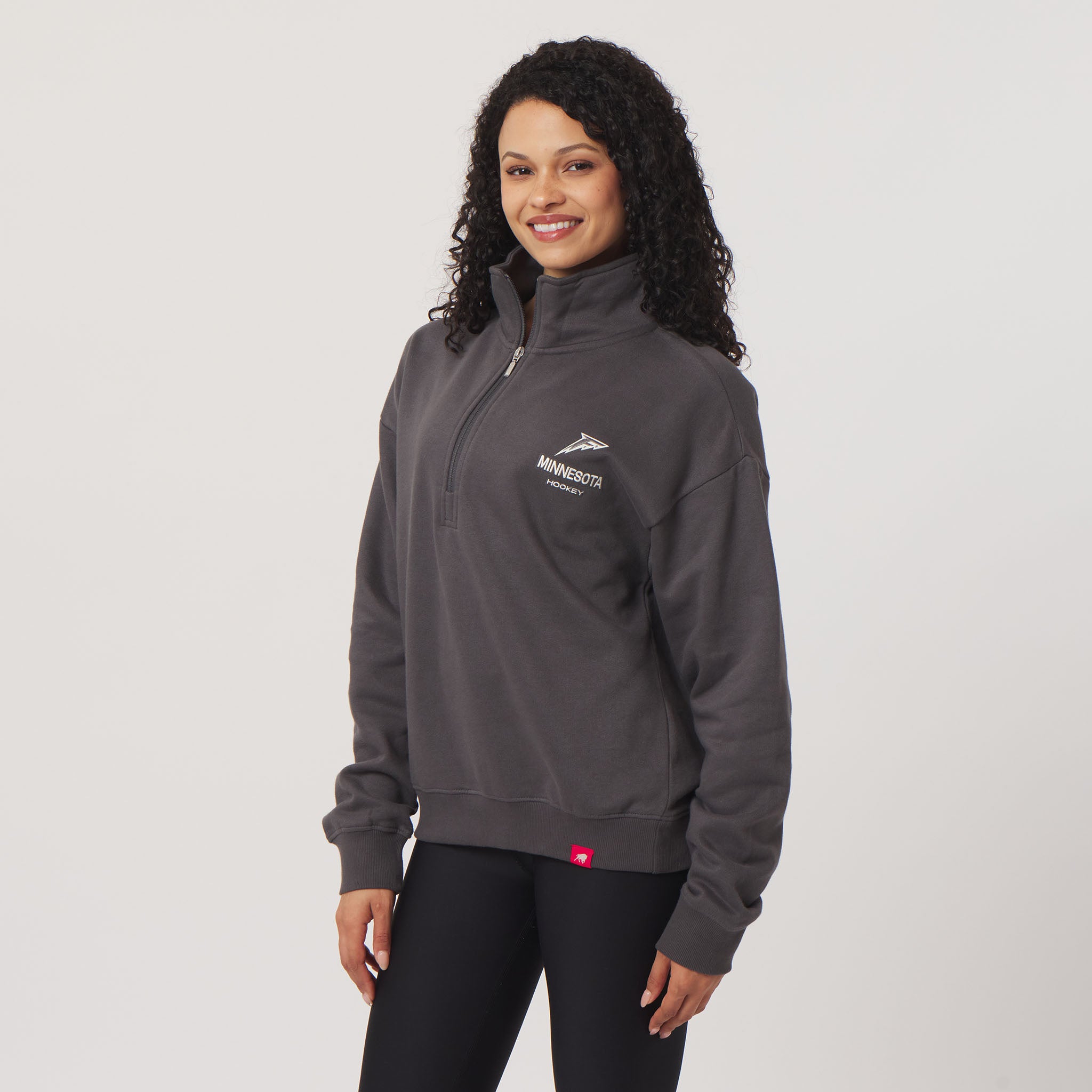 Woman wearing a gray pullover with a logo on a white background