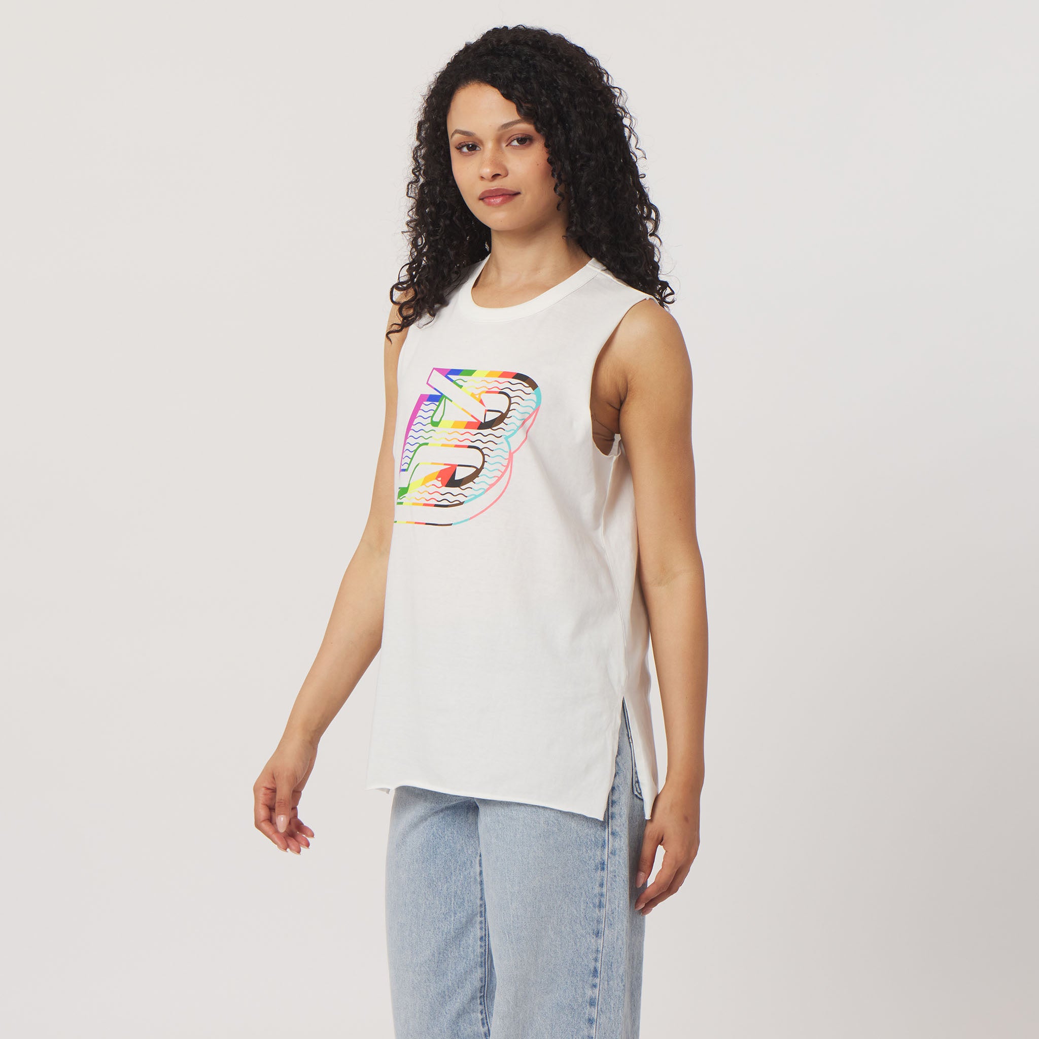 Woman wearing a white sleeveless shirt with a colorful graphic design on a plain background