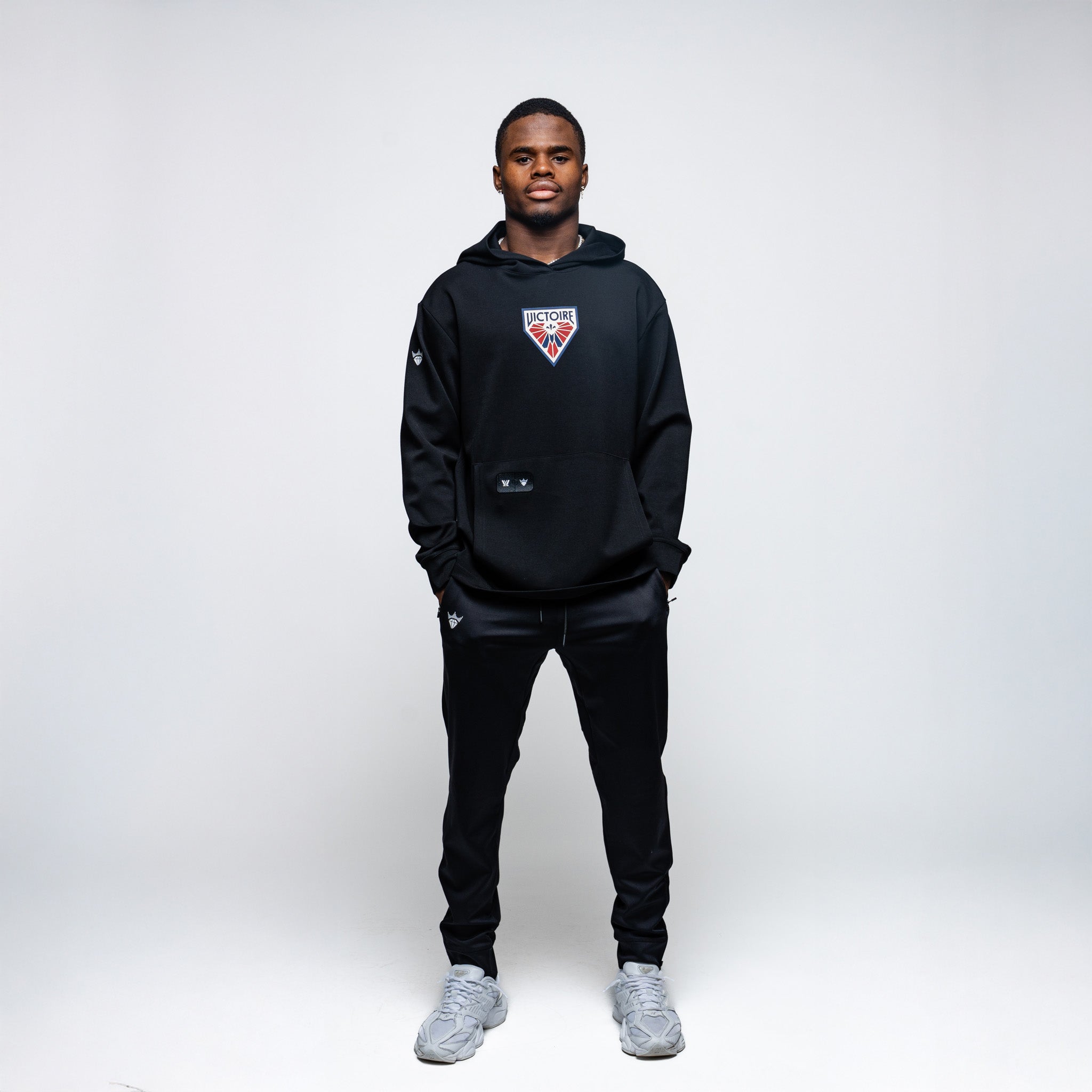 Person wearing a black hoodie with a logo on a white background