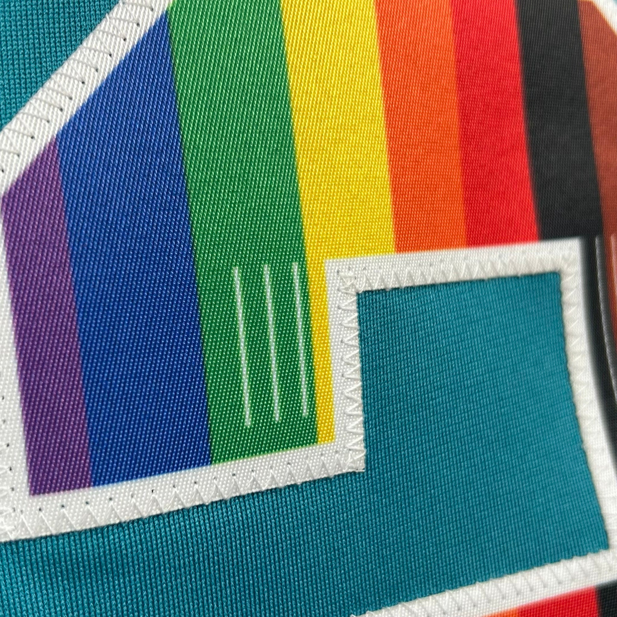 Colorful fabric patch with rainbow pattern and text on a teal background