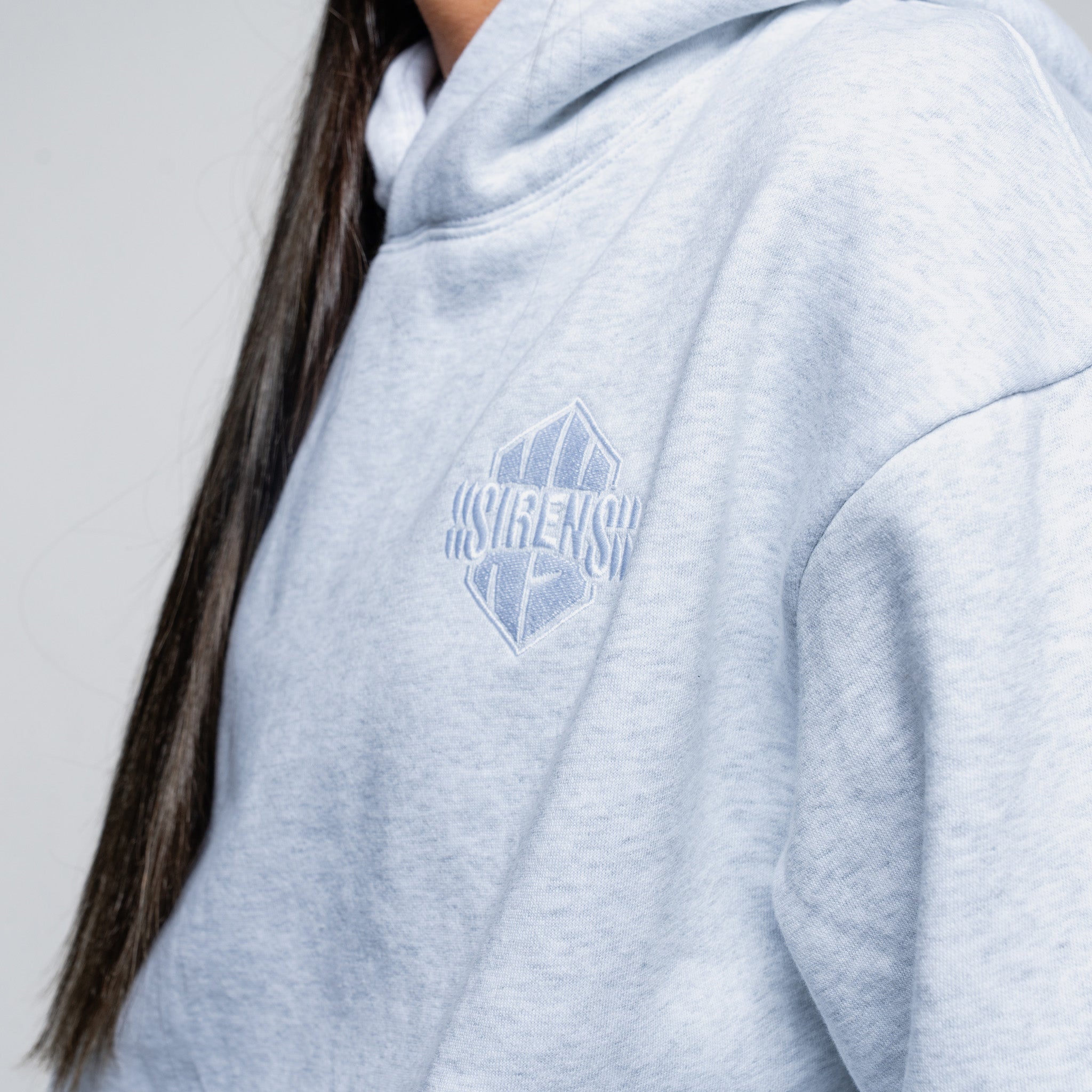 Light blue hoodie with a logo on the chest against a neutral background