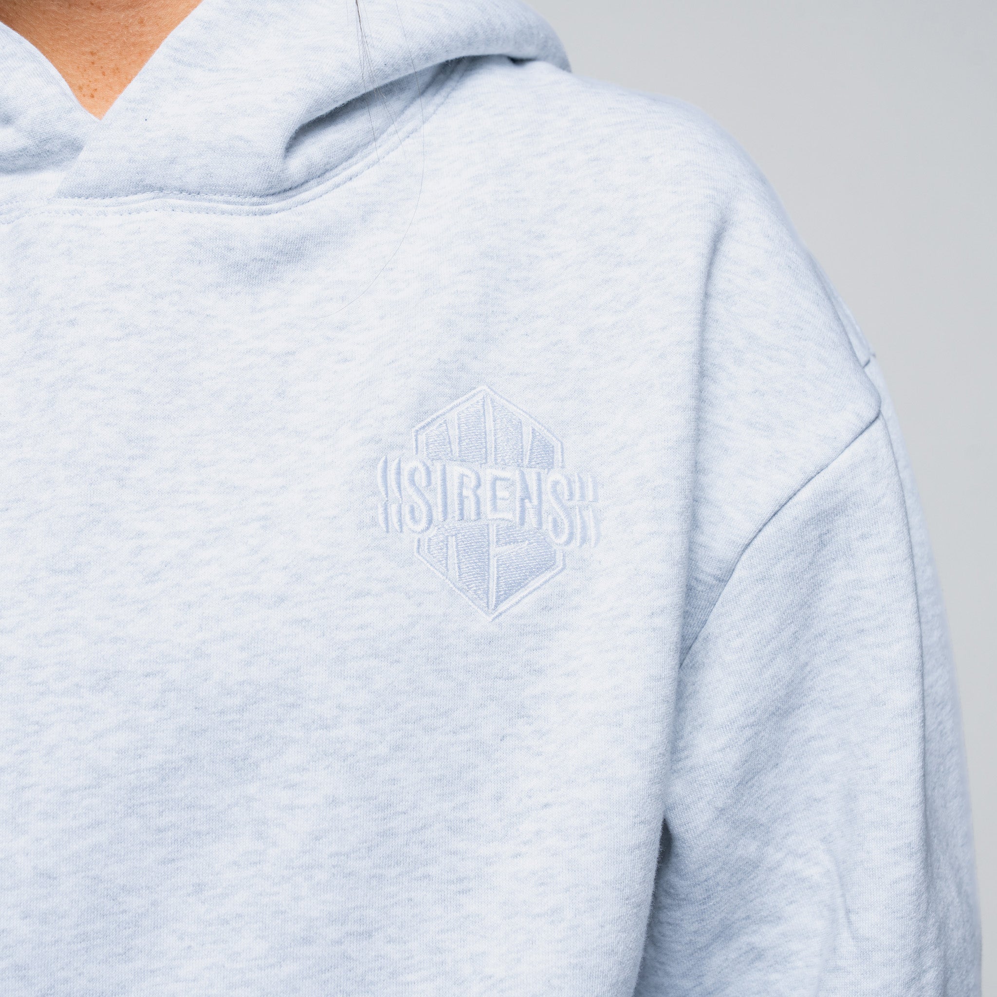 Light blue hoodie with a brand logo on the chest against a neutral background
