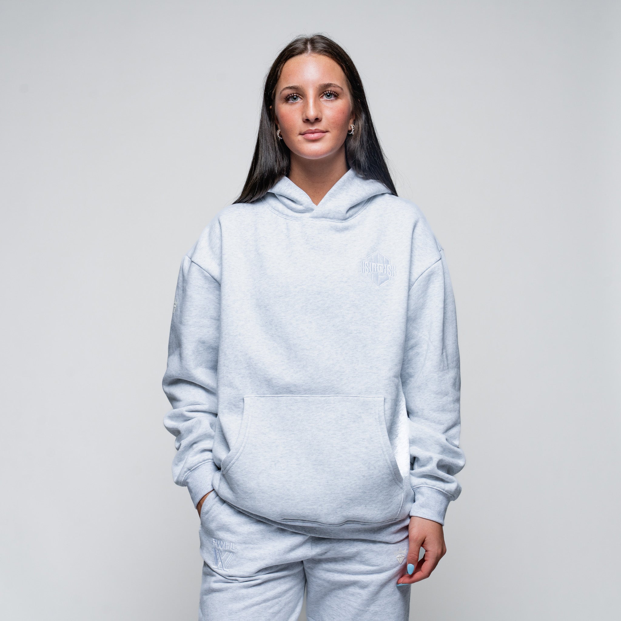 Person wearing a light gray hoodie and pants on a plain background