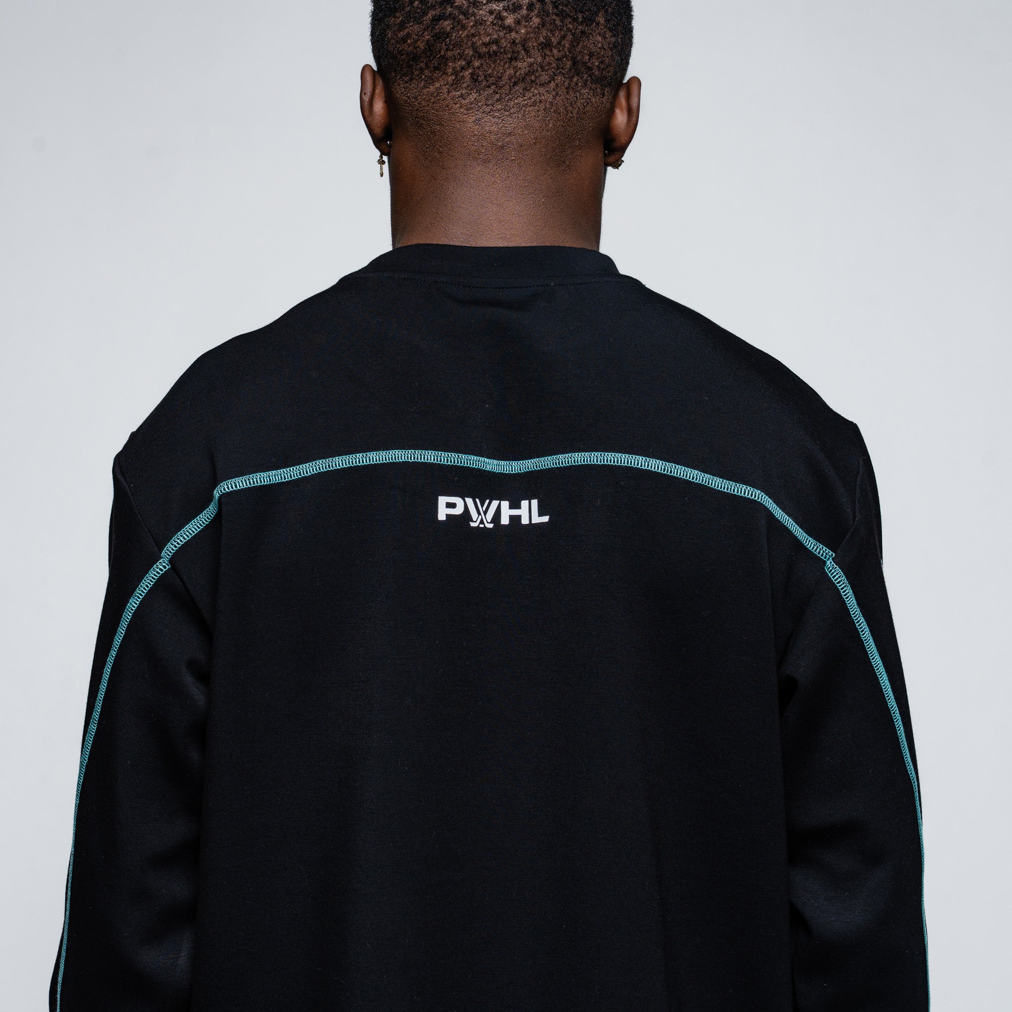 Person wearing a black sweater with 'PWHL' logo on the back against a light gray background