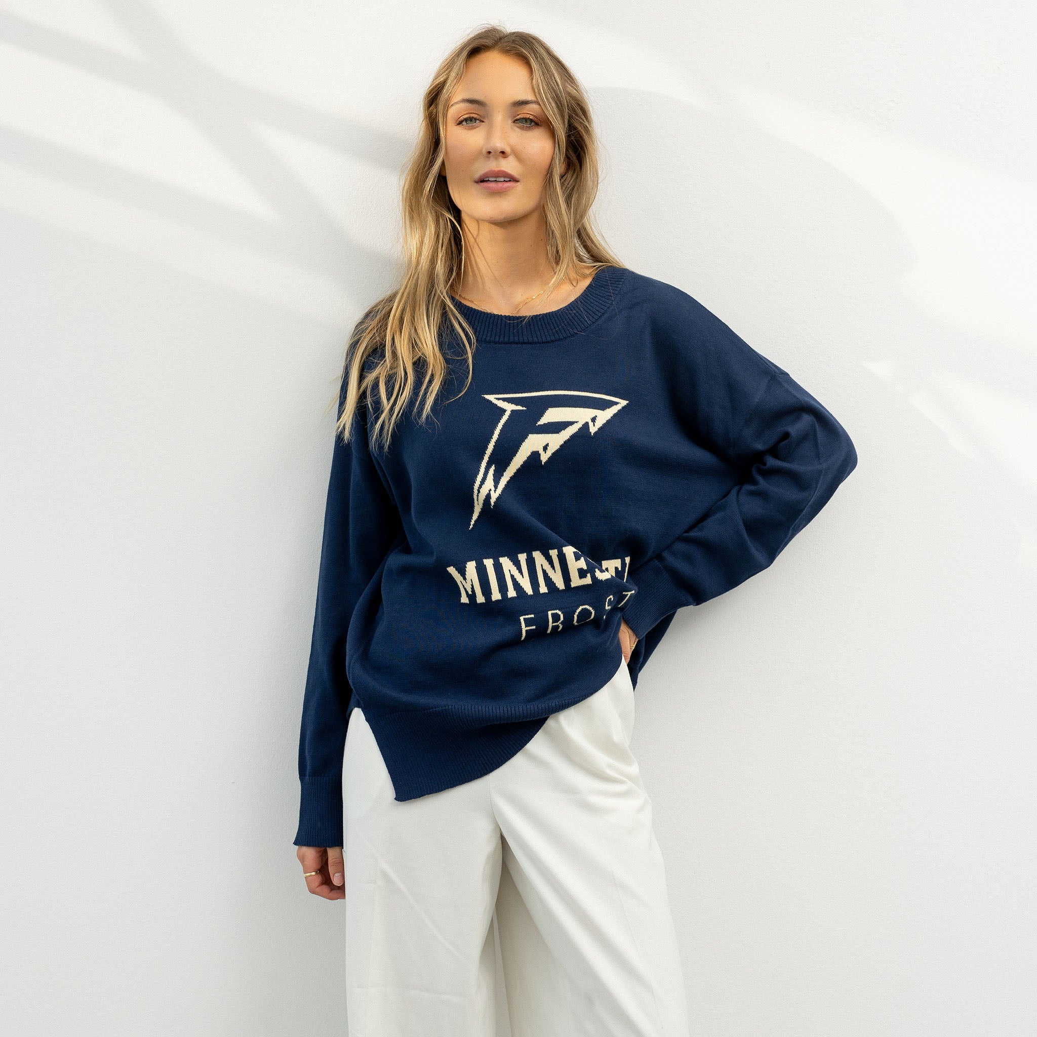 Woman wearing a navy blue sweatshirt with a logo and text against a white background