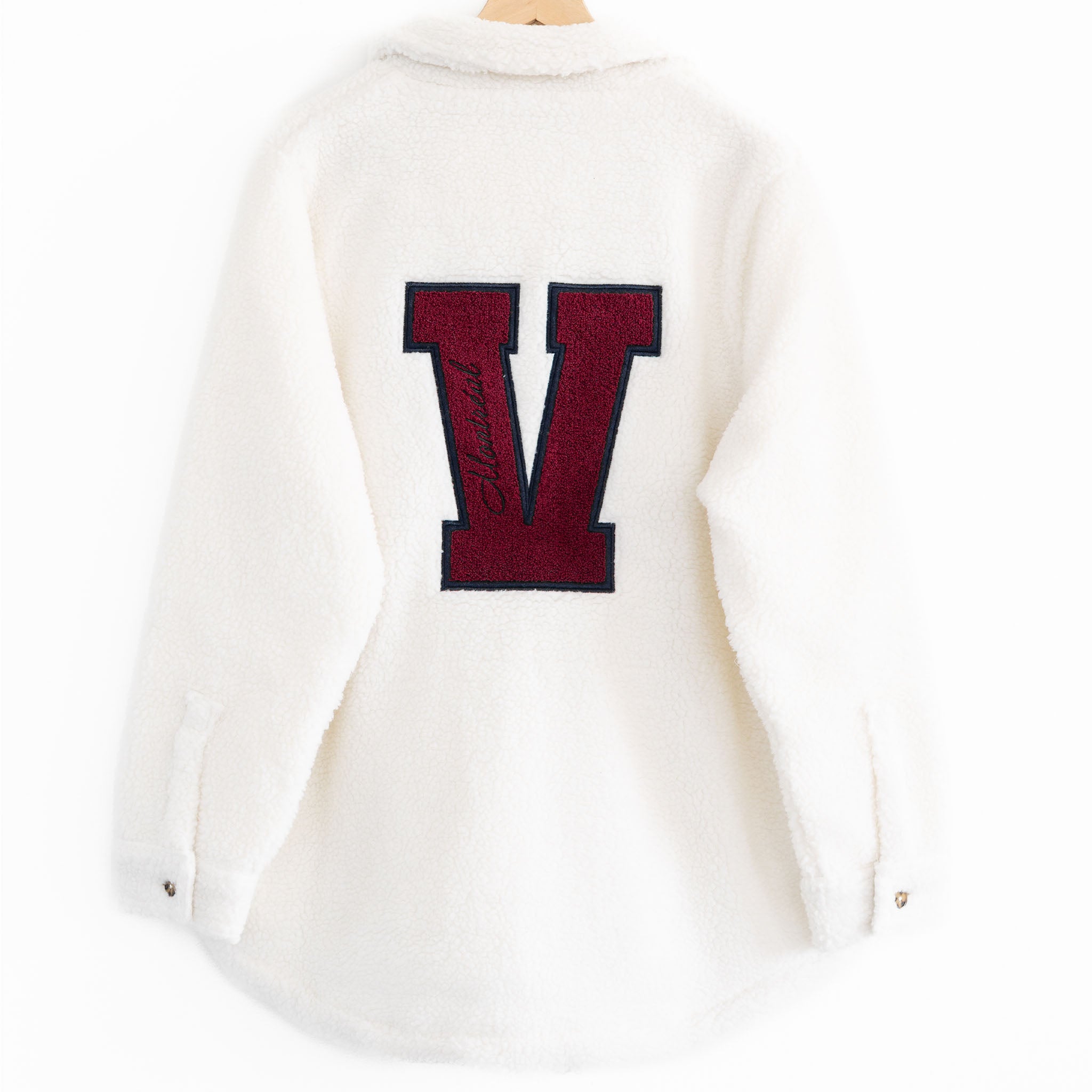 The back of a White Sherpa Jacket with a maroon V that says Montreal inside it
