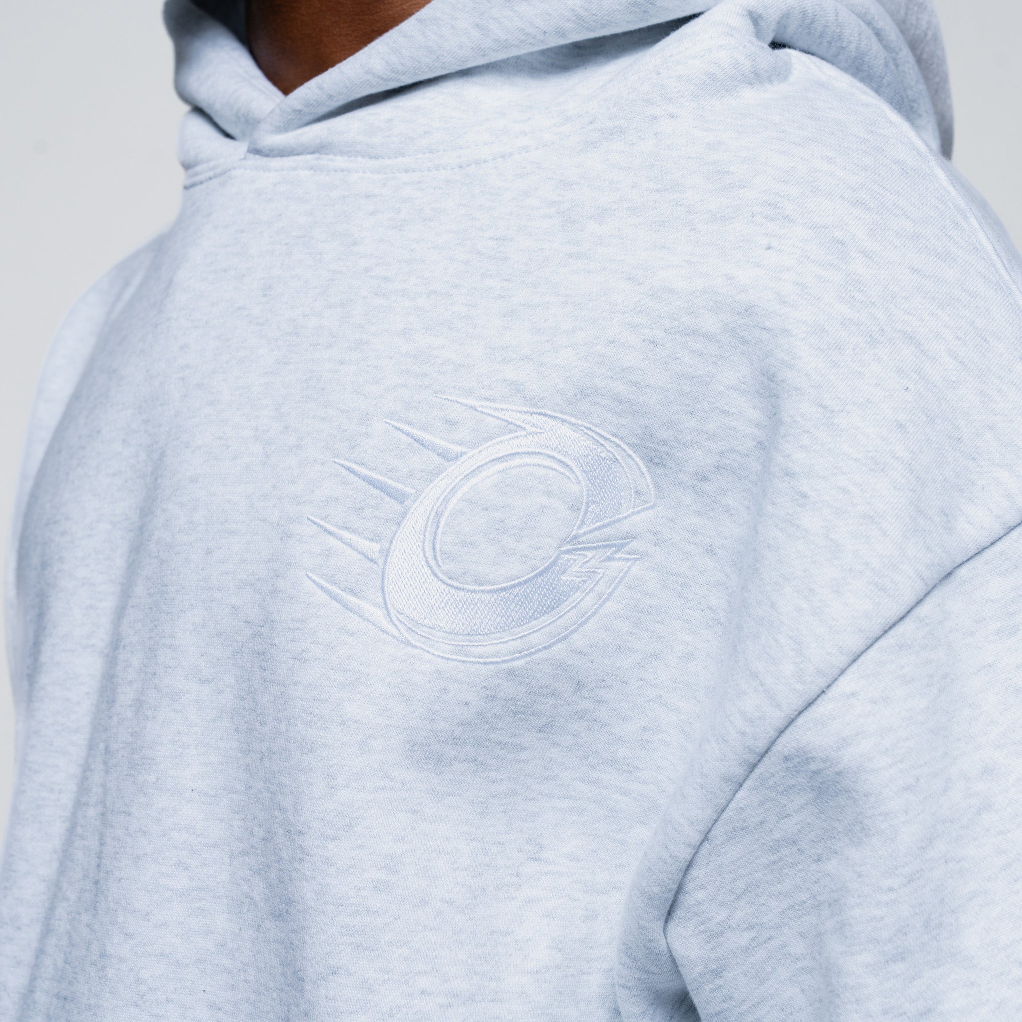 Light grey hoodie with a logo on the chest against a neutral background