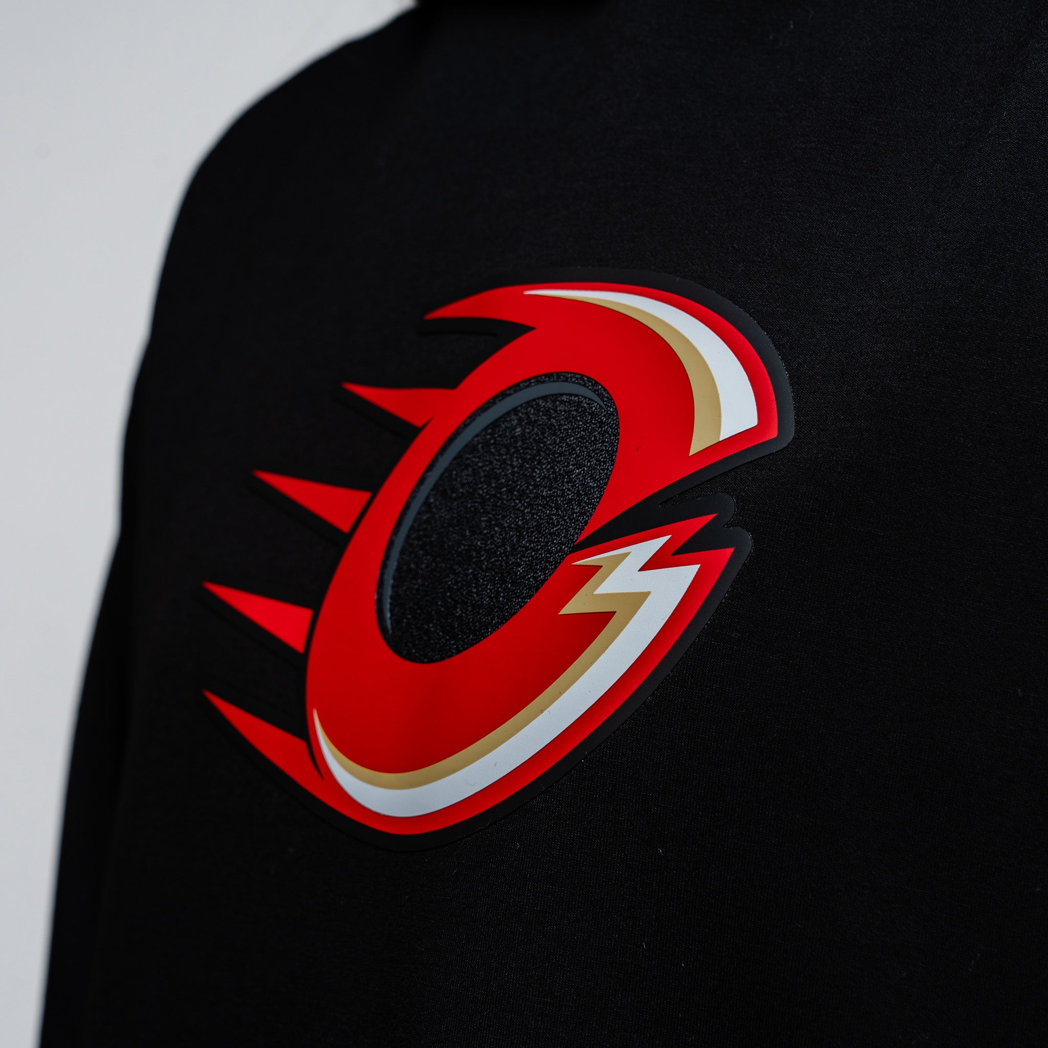 Black sweatshirt with a red and white logo on a gray background