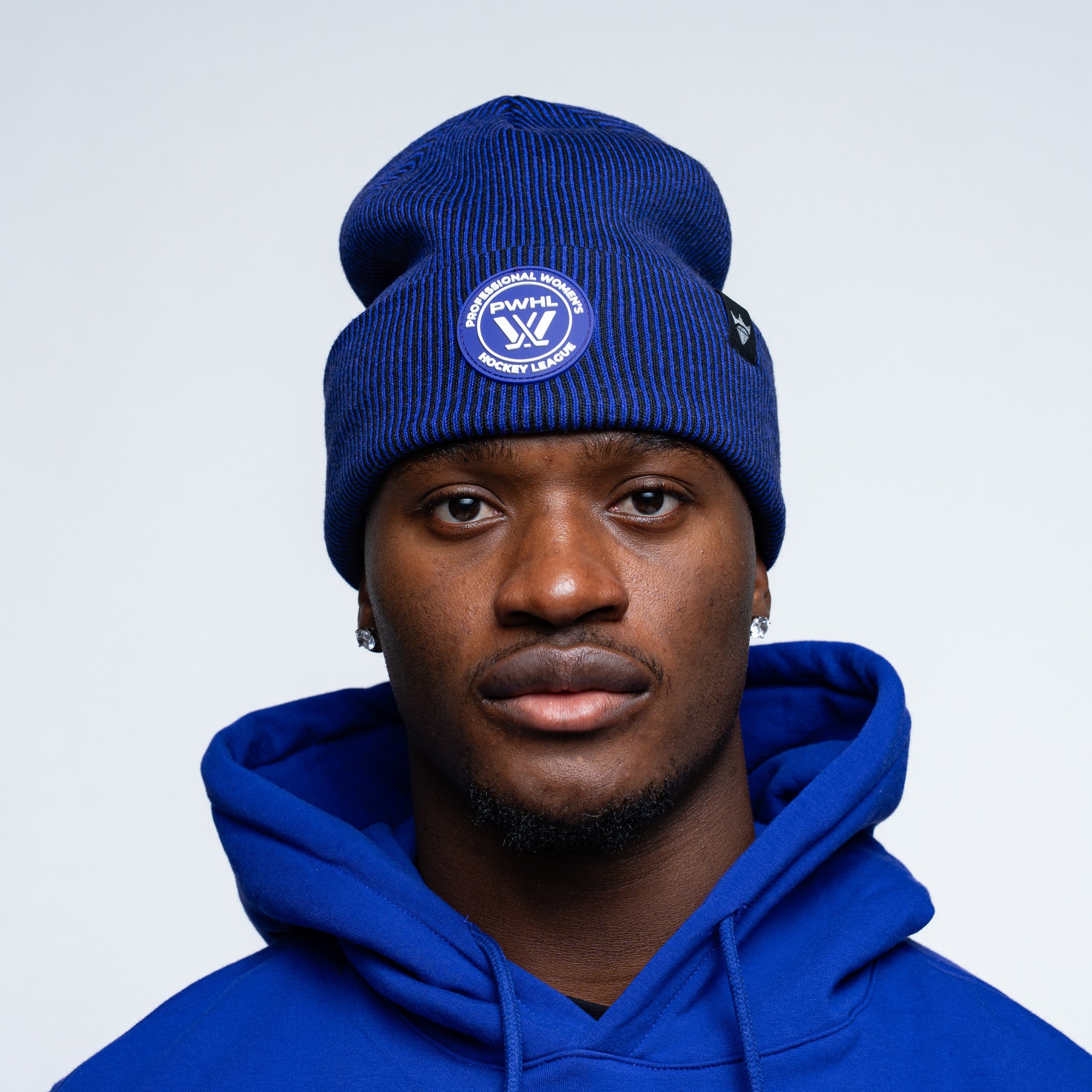 Person wearing a purple beanie and hoodie with a logo on a light gray background