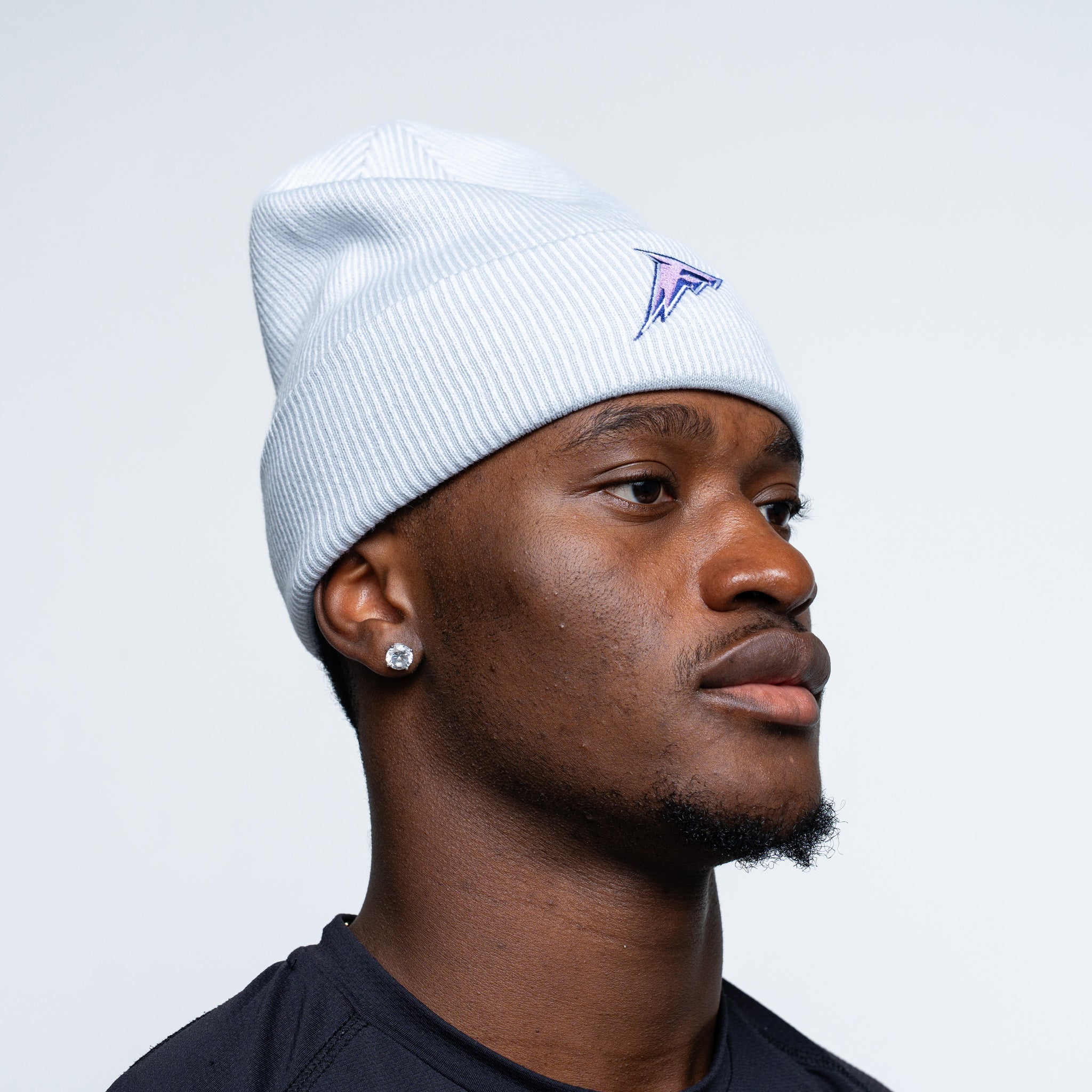 Man wearing a white beanie with a logo on a light gray background