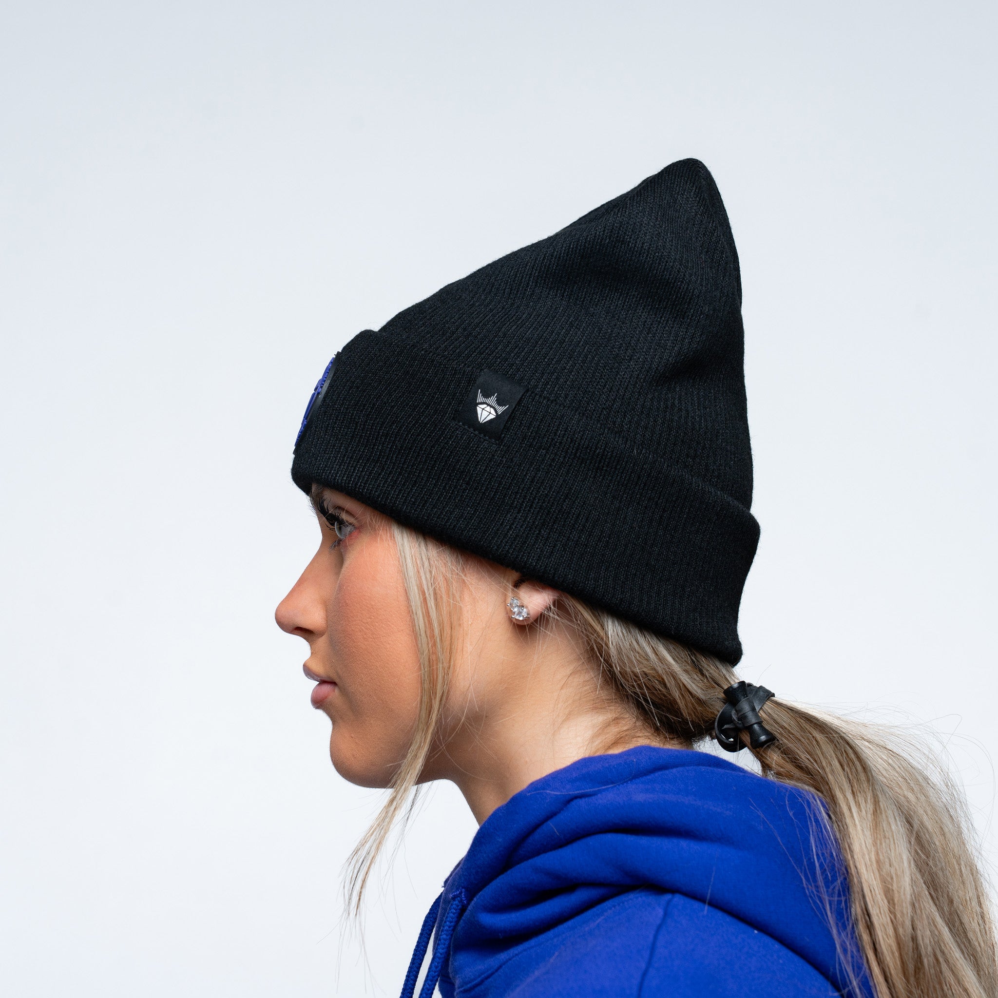 Person wearing a black beanie and purple hoodie on a white background