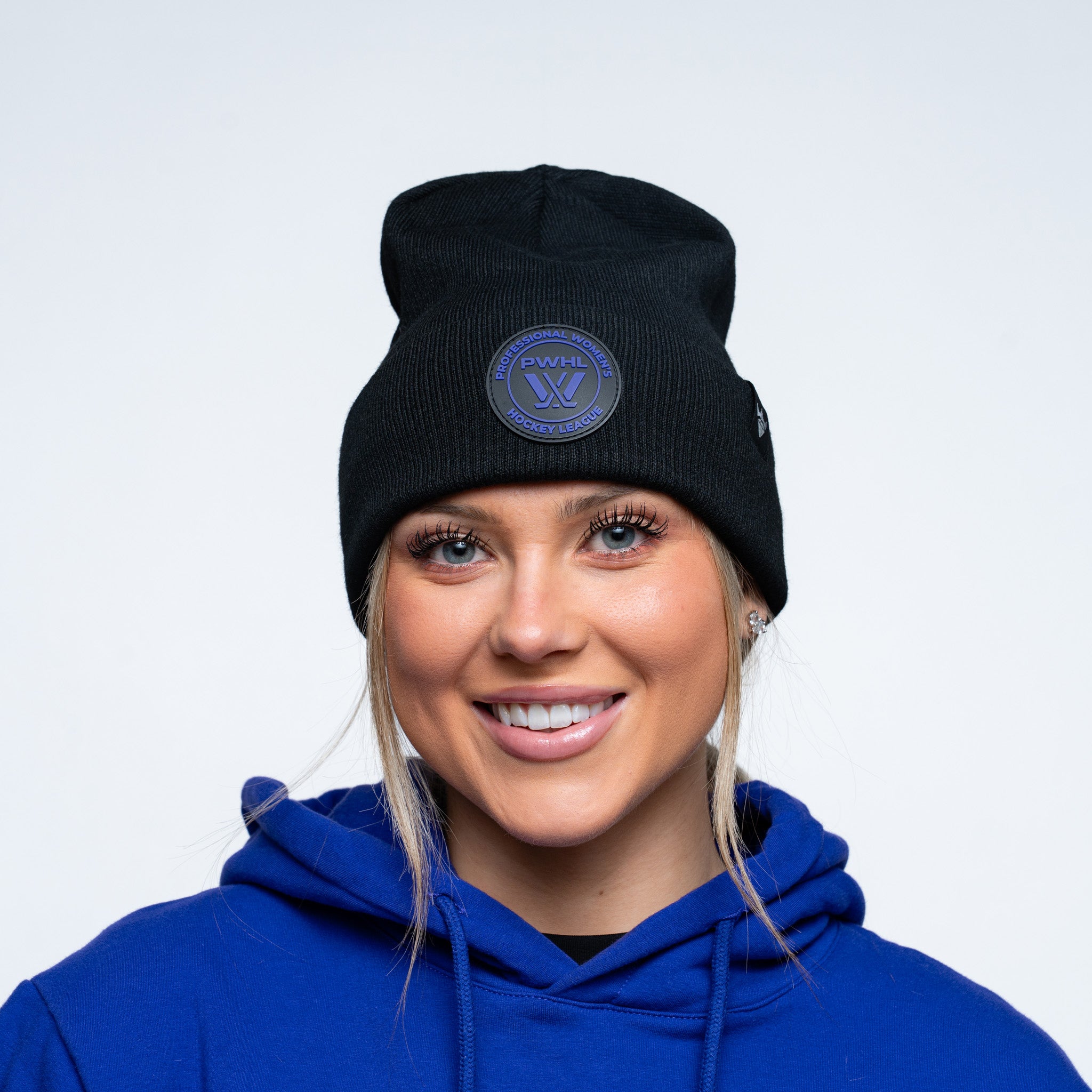Person wearing a black beanie with a logo and a purple hoodie on a white background