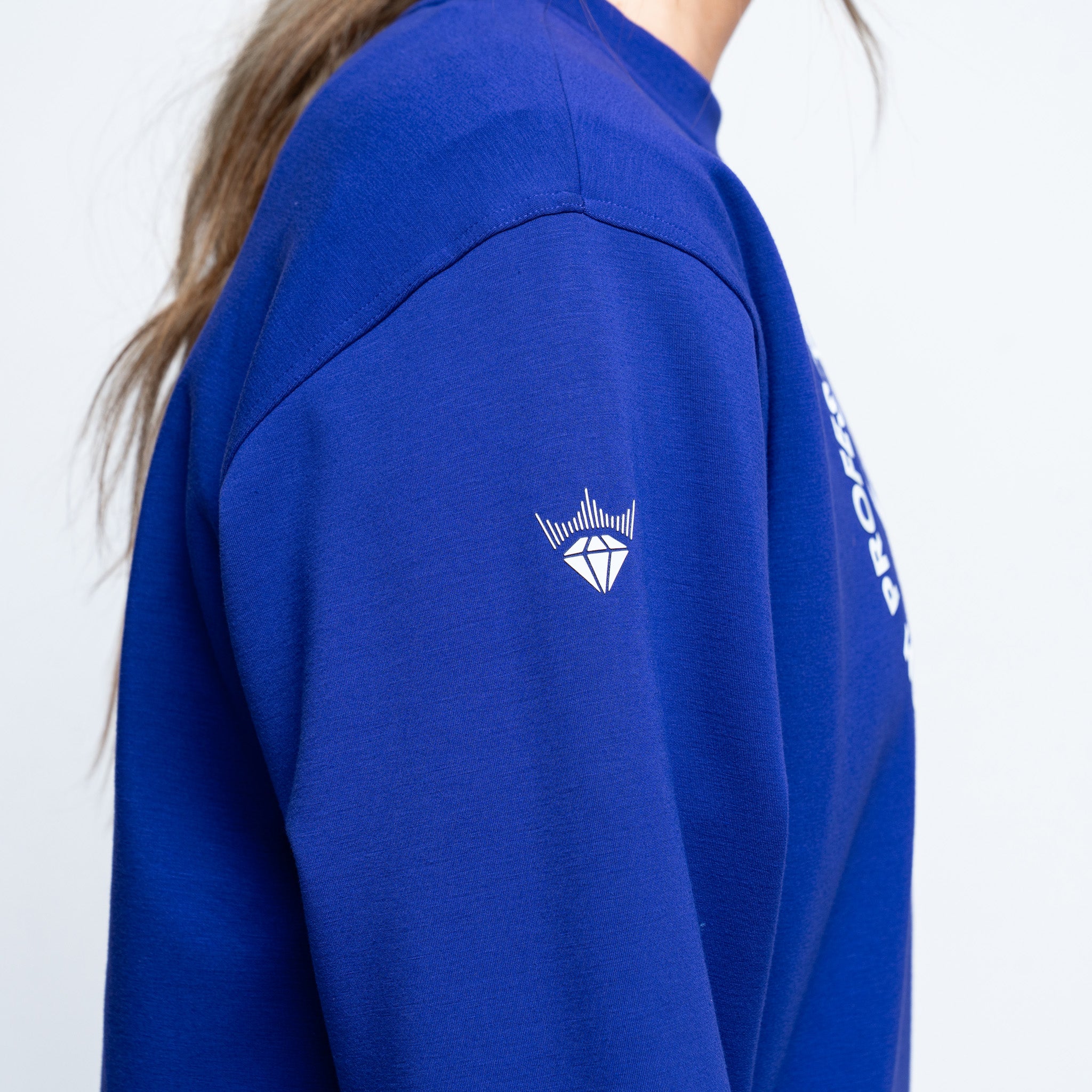 purple sweatshirt with a logo on the chest and text on the sleeve against a white background