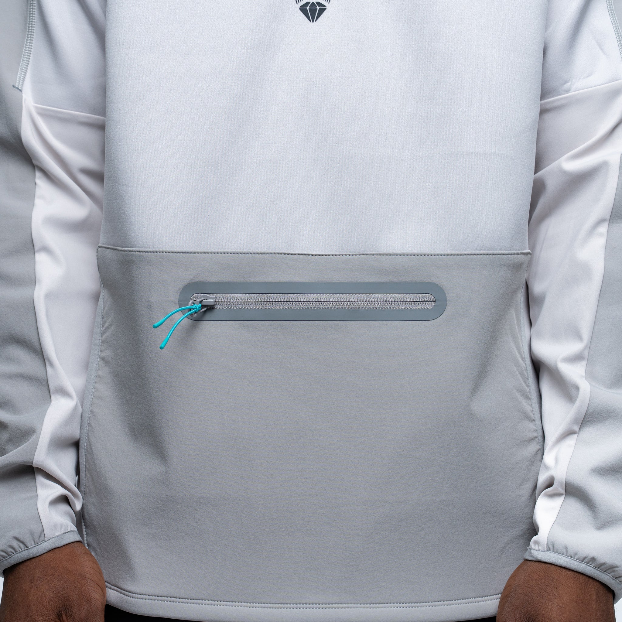 Close-up of a light gray jacket with a zipper pocket and brand logo.