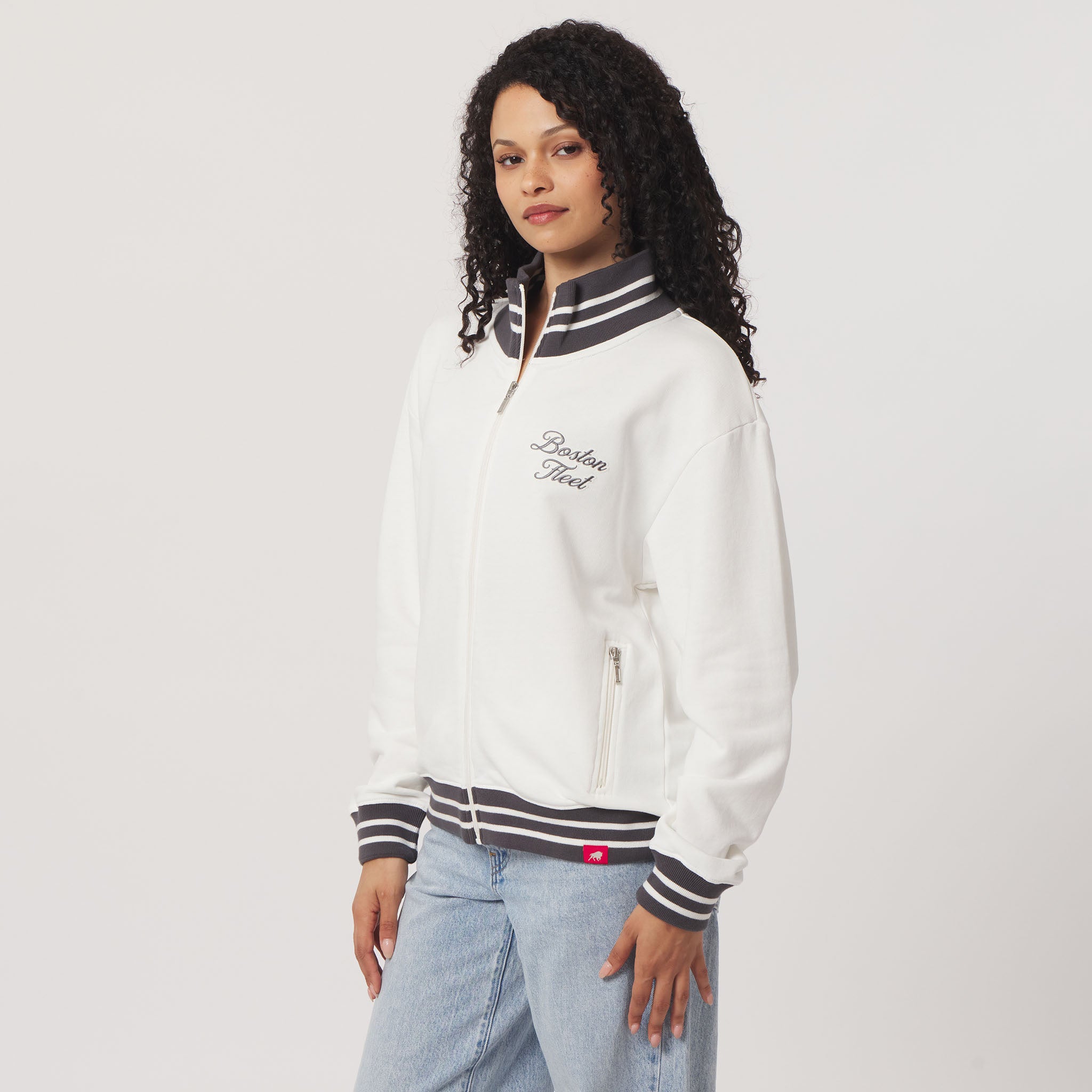 Woman wearing a white jacket with black and gray accents on a light gray background