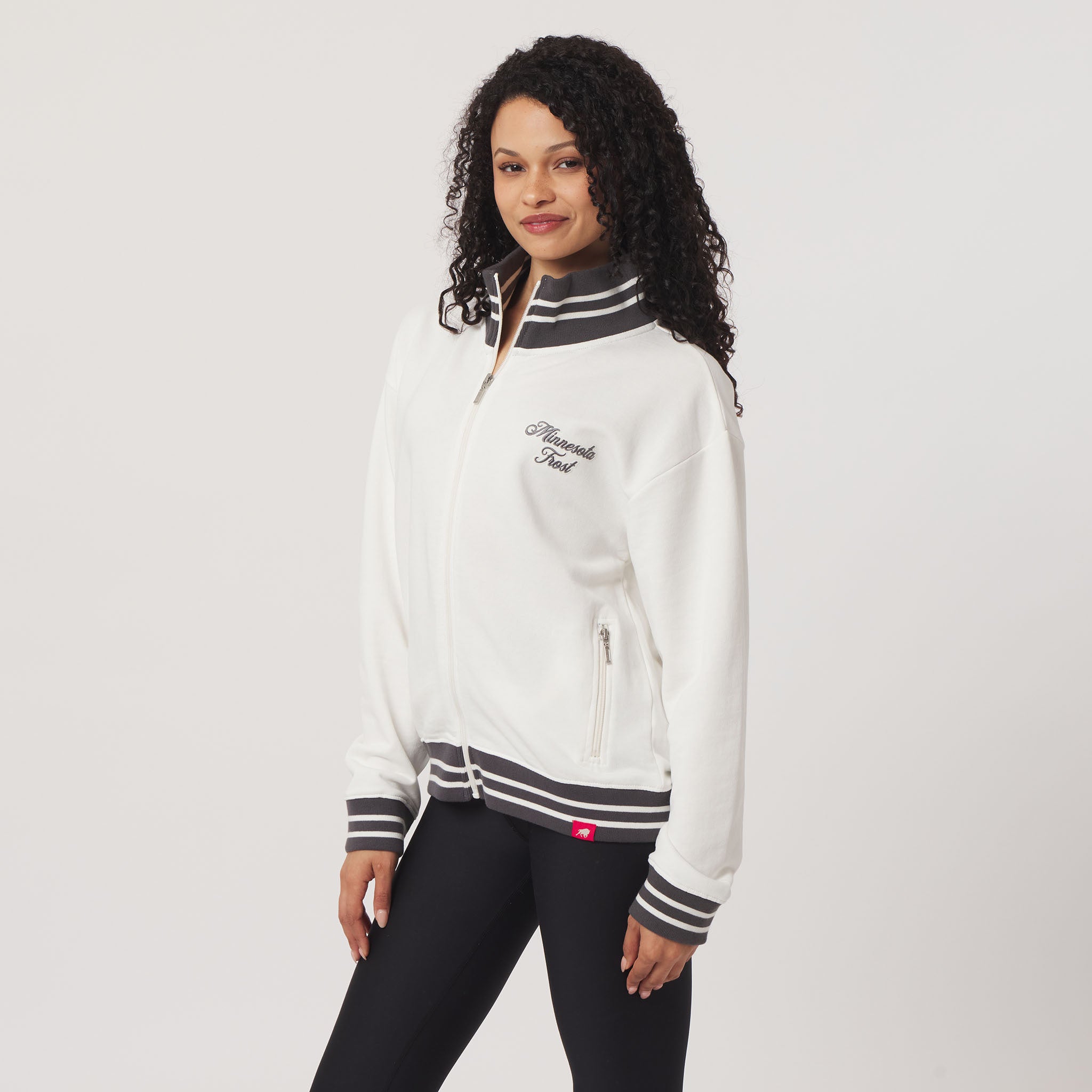 Woman wearing a white and black tracksuit with visible branding on a plain background