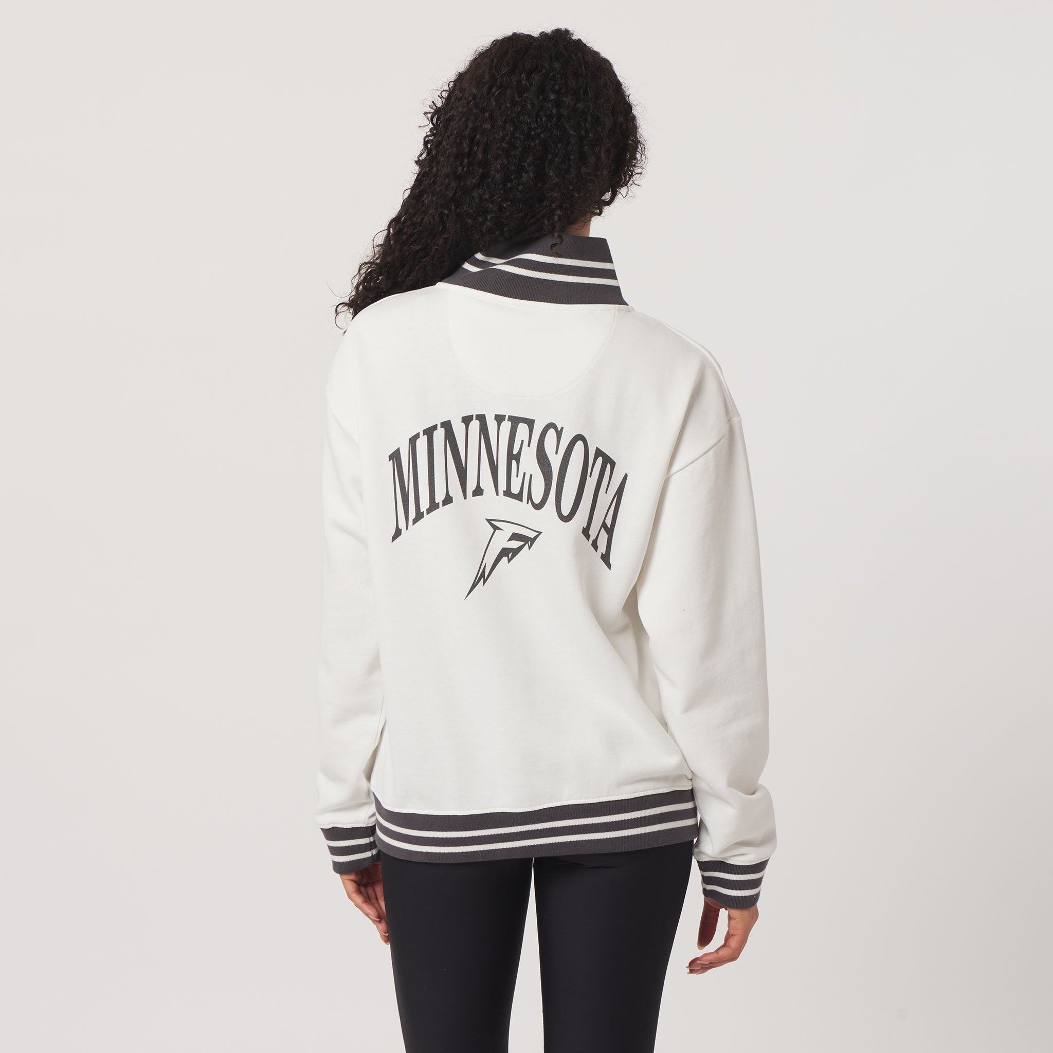 Person wearing a white varsity jacket with 'Minnesota' printed on the back against a light gray background