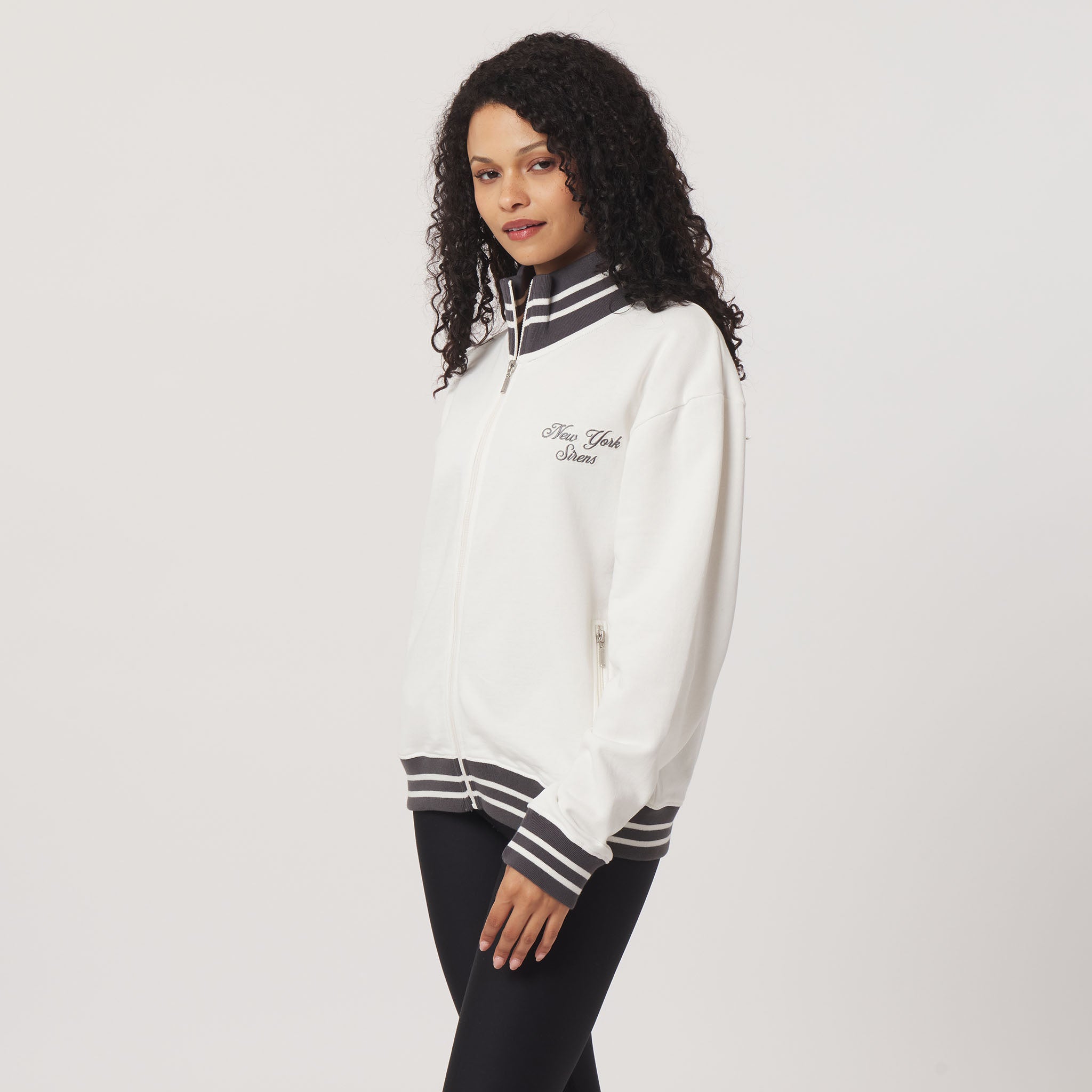 Woman wearing a white sweatshirt with black and gray accents on a plain background