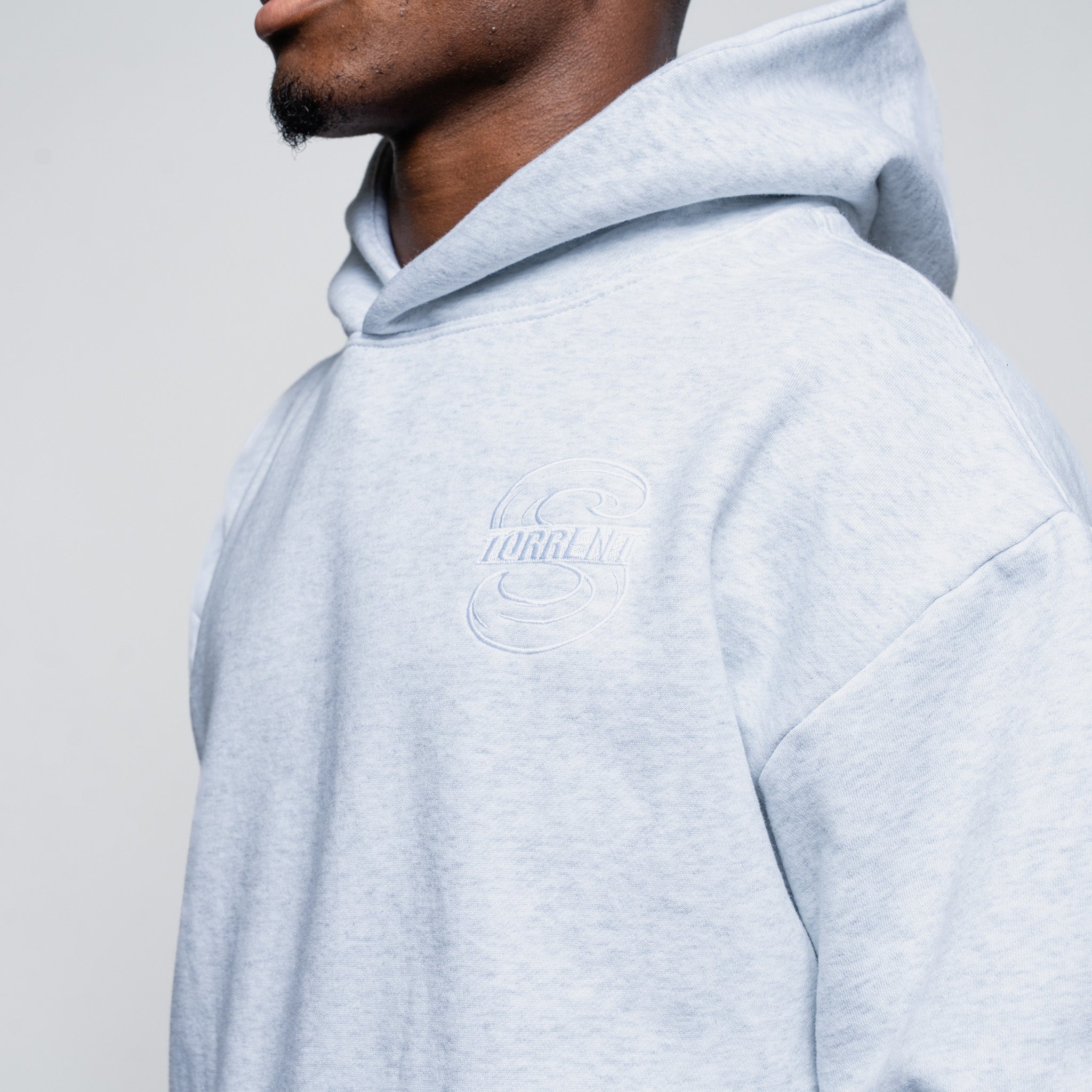Person wearing a light gray hoodie with a brand logo on a plain background