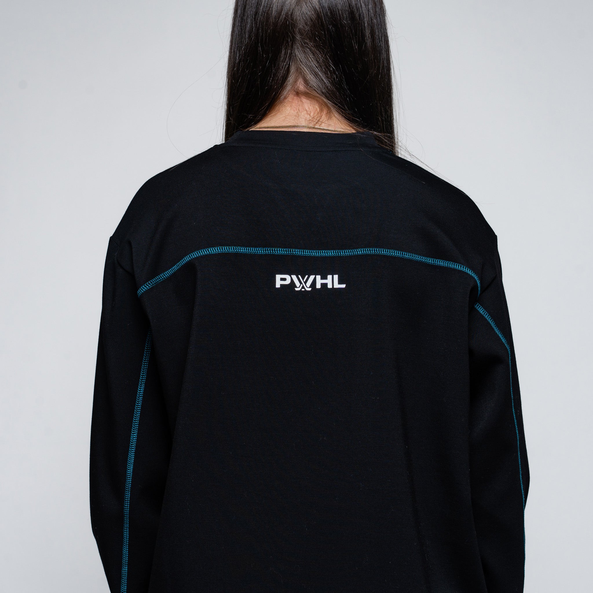 Person wearing a black jacket with a logo on the back against a gray background