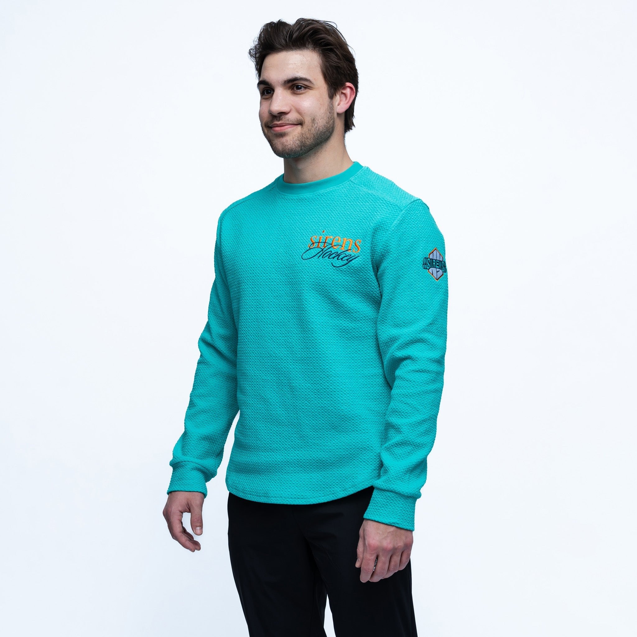 Man wearing a teal sweatshirt with branding on a white background